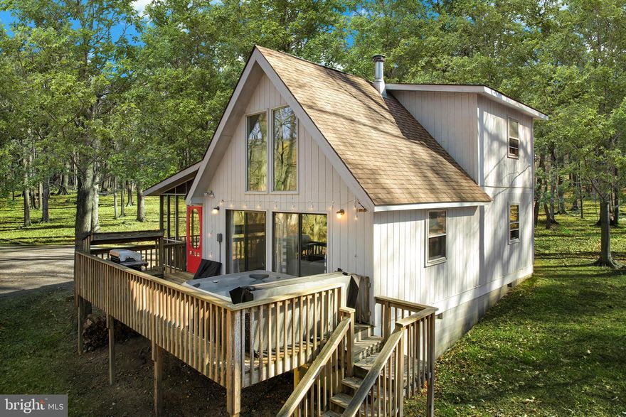 Stylish chalet-style cabin with soaring ceilings and an open-concept living area filled with natural light – and just five minutes from Cacapon Resort State Park!  The inviting living room flows seamlessly into a well-appointed kitchen with a spacious dining area.  Enjoy multiple outdoor spaces, including a spacious deck with a hot tub and a screened-in porch.  As a vacation rental it has generated over $100k over the past two years ($46,000 in the past year alone), and can come with an existing property manager and cleaner.  Hot tub and furniture optional, available for purchase.  See seller docs for a summary of rental history and financials.  $1,000 buyer credit if you continue using the same property manager.  Perfect vacation home or investment property!