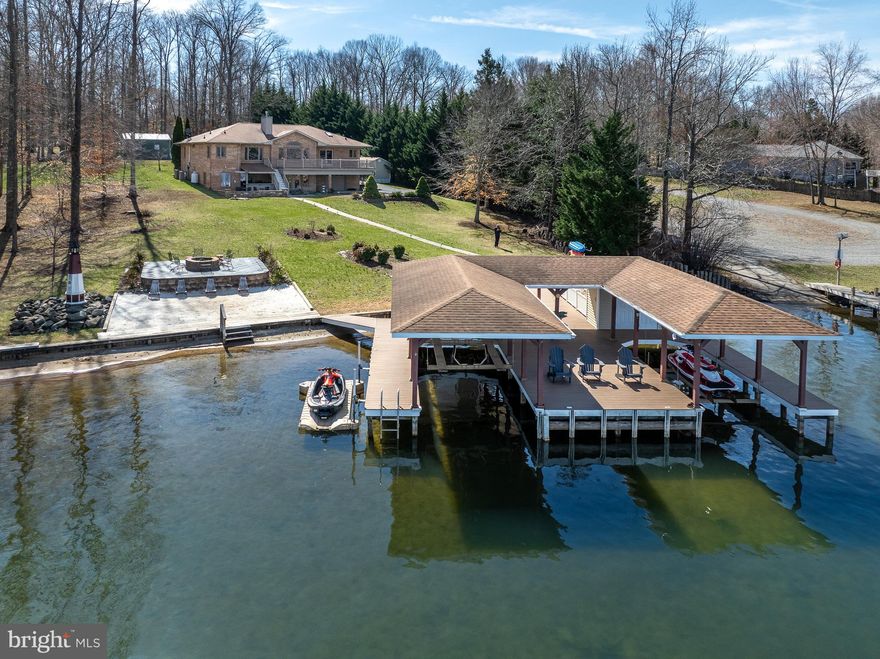 Turn-Key Waterfront Oasis at Lake Anna, Virginia. Discover the perfect lakefront retreat in the sought-after Cuckoo’s Nest subdivision on the private side of the lake. This fully furnished waterfront home offers breathtaking views and comes with two jet skis, a golf cart, an ATV, and kayaks—everything you need for endless fun on the water! Everything in the garages and the sheds also convey; including the motorcycle! Built with classic all-brick construction, this spacious 3,812 Sqft home features 5 bedrooms, 3 full baths, and an inviting open floor plan designed for relaxation and entertainment. The family room features hardwood flooring, vaulted ceilings, a stone gas fireplace, and a wall of windows showcasing stunning lake views. The kitchen is equipped with hickory cabinets, stainless steel appliances, a breakfast bar, and a walk-in pantry, flowing seamlessly into the dining area for effortless gatherings. The main-level lakeside primary suite features a walk-in closet and a renovated bath with tile flooring, a tiled shower, double vanity, and a freestanding soaking tub. Two additional bedrooms, a full bath, and a convenient laundry room complete the main level. The walkout lower level offers additional entertainment space, including a large family room, recreational area, wet bar, two bedrooms, and a full bath. Plus, a built-in one-car garage provides ample storage for lawn equipment and lake toys. Step outside to 180 feet of bulkheaded waterfront, your own private sandy beach, a stone patio with a fire pit, and a covered boathouse featuring two slips with electric lifts, a storage room, tiki bar, sun deck, and a jet ski pad. Additional outdoor amenities include a concrete patio, outdoor shower, outdoor kitchen/bar area, and a spacious composite deck. For all your storage needs, the property also includes a two-car attached garage, oversized detached garage/workshop, two-car carport, multiple sheds, and a paved driveway. Nestled on a beautiful private .96-acre lot, this low-maintenance home lets you relax and enjoy lake life to the fullest. Located just minutes from local dining and grocery stores, it’s the perfect getaway or full-time residence.  The home can sleep up to 20 people, has a rental history and brought in $94k through VRBO alone one year. Golf cart friendly community!