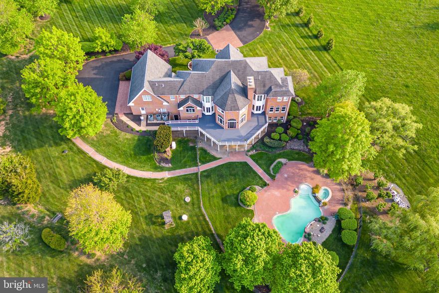 Stunning 5.5+ acre estate on your own private oasis.  With zoning changes in sought-after Loudoun County, this expansive, private lot is becoming a rarity. This fully-brick home, open two-story foyer and stunning travertine stone tile floors. The rest of the main level features beautiful hardwood floors, high ceilings, crown molding, wainscoting trim package, built-in shelving, gourmet eat-in kitchen with granite countertops, Viking 5-eye gas stove with recessed vent and Viking double oven, sunroom, great room with gas remote-controlled fireplace, 2 half baths, separate dining room, and a large space that can serve as a living room/music room/library/office . . . and every window has a picturesque view! Three recently-installed HVAC systems. Never worry about emergency power outages with the new, whole-house Generac generator. It is fueled by the 1,000 gal. underground propane gas tank that you own. Bonus: the tank is nearly full and conveys to the new owners. The main level family room opens to the newly-painted deck that wraps around the back of the most tranquil setting, overlooking the pool and distant woods. There are 2 staircases leading to the upper level: no carpet in any of the rooms! French doors with transom window onto the hardwood floors of the large master suite. Inside, there’s a grand fireplace, an adjacent sitting room, floor-to-ceiling bookshelves, and a large walk-in closet. The spacious master en suite features double sinks with natural, stone custom countertops, separate shower and toilet areas, and a gas fireplace to set the mood while you relax. Each of the additional 3 large bedrooms upstairs has its own en suite bathroom. The spacious upstairs laundry room features a large capacity dryer, a new Samsung smart washer, utility sink with granite countertop. The lower level is not an ordinary basement, but a fully-finished English walkout with high ceilings and lined with windows, providing a full third floor of luxury and entertainment possibilities. This level features new travertine stone tile flooring; a remote-controlled gas fireplace; and a beautiful new bar with quartz countertops, stainless steel sink, and high end wine and beverage cooler. Two spaces here are large enough for a pool table, so take your pick! One of the rooms features a custom built-in wine closet and would make a perfect wine-tasting room or theatre. A bedroom is also tucked away in the lower level. This entire space can be an in-law/visitors own private apartment. The bathroom features an oversized shower and plenty of closet space. Never run out of hot water with 2 tankless water heaters! The basement has 2 sets of large French doors that walk out to the recently-installed, lighted stone path and recently-refinished stone deck.  The spa and pool were both upgraded in 2019. The pool has a graduated entry to a depth of 5’ . It can be conveniently controlled remotely through the new Pentair operating system/warmed with the electric heat pump. The lot of this custom home was meticulously graded and designed with French drains.  There are 3 Nest thermostats, Culligan water softener, 3-car garage with spare refrigerator/freezer. Updates: whole house Generac GENERATOR (May 2022)/3 new garage remotes (2023) Samsung 5.2 cf lg capacity smart top load washer (2022)/3 new HVAC units (2020 and 2022) w/ extended warranties transferable to the new owner/Kitchen and Bar cabinets refinished (2022)/New pool operating system PENTAIR w/remote capability (2021)/New landscape, path and spot lights (2021)/Updated basement bar w/ quartz counters (2021)/TYLZA wine and beverage refrigerator 24 inch dual zone wine cooler(2020)/Driveway resurfaced (2020)/New septic lid and pump (2020)/New pool decking and new sidewalk path; pool and hot tub resurface (2019)/New dishwasher, water tank, and 2 tankless water heaters (2019)/Purchased underground 1,000 gal propane gas tank can be filled by any vendor. (2019)/Dolphin pool cleaner, pool pump/ motor(2018)
