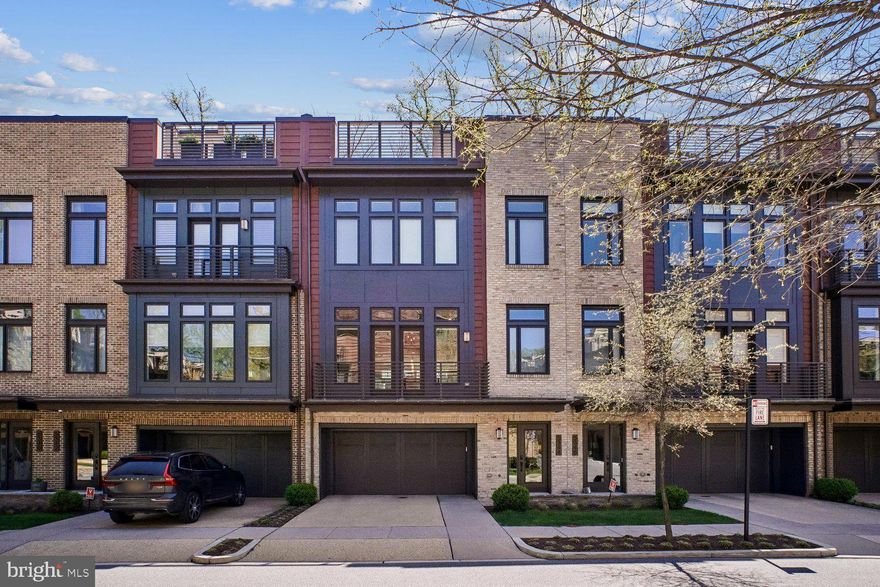 Experience refined townhome living in coveted Grosvenor Heights. This exceptional EYA Harrison model offers three features distinguishing it from other models in the neighborhood: a full driveway providing 2 parking spaces in addition to the EV equipped 2-car garage, a fully fenced rear yard for privacy, and beautiful treed views from every level and the rooftop deck. Offering approximately 3,400 sq. ft. of finished space, with an elevator-served layout designed for comfort and convenience. The sunlit main level showcases dramatic 10-foot floor-to-ceiling windows and is ideal for entertaining, with a gourmet kitchen, oversized island, spacious dining area, and a great room with a fireplace. The entry level includes versatile living options with a full bath—perfect flex space for a home office, guest suite, additional family room, art studio...the possibilities are endless. Upstairs, 9-foot ceilings accentuate the airy feel, with a privately situated primary suite on one side and two additional bedrooms with a full bath on the other—an ideal layout for everyday living or guests. Thoughtful finishes throughout reflect EYA’s award-winning craftsmanship. Enjoy low HOA fees and exceptional convenience—less than a mile to Grosvenor Metro, the Bethesda Trolley Trail, Fleming Park, Wildwood Shopping Center, Grosvenor Market, Strathmore Hall, and major routes including I-495 and I-270. Sophisticated but comfortable, sunlit, and superbly located—this is a rare offering in Grosvenor Heights.
