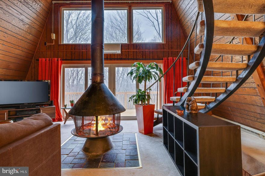 STUNNING CHALET-STYLE WITH BREATHTAKING STYLE VIEWS IN THE HEART OF THE POCONOS WITH A MID CENTURY MODERN VIBE... Nestled against the serene backdrop of state game lands, this UNIQUELY designed 3-bedroom, 2.5-bathroom home offers the perfect blend of luxury, comfort, and nature. With no neighboring homes behind you, enjoy total privacy and unparalleled tranquility, all while being just minutes away from Big Boulder Ski Resort, Pocono Raceway, Lake Harmony, Mt. Airy Casino, and all the best Poconos attractions. As you step inside, you're greeted by an open concept floor plan that seamlessly integrates the living, dining, and kitchen areas. The centerpiece of the living room is a stunning carousel-style, free-standing wood-burning fireplace, perfect for cozy evenings. The reclaimed railroad track staircase adds an architectural touch, bringing history and charm to the home. The kitchen and living spaces offer beautiful views of the surrounding landscape, visible through large windows and from the expansive back deck—ideal for entertaining or simply soaking in the peaceful surroundings. Two brand-new decks provide ample outdoor space for relaxation, dining, or enjoying the scenic vistas. The master suite is a true retreat, with a spacious layout and an en-suite bath featuring a specially insulated soaking tub that keeps water warm longer. The downstairs bathroom includes radiant floor heating for extra comfort. The basement is designed for relaxation and entertainment, with a full bar, sauna, and Bluetooth-enabled fans and lights that let you stream music throughout the space. The downstairs also features a unique river rock wall with a built-in fountain, adding a touch of tranquility to your home. Outside, the freshly painted exterior and two-car garage are complemented by a beautifully maintained home, and with direct access to the surrounding nature, you'll have the perfect mix of modern convenience and rustic charm.