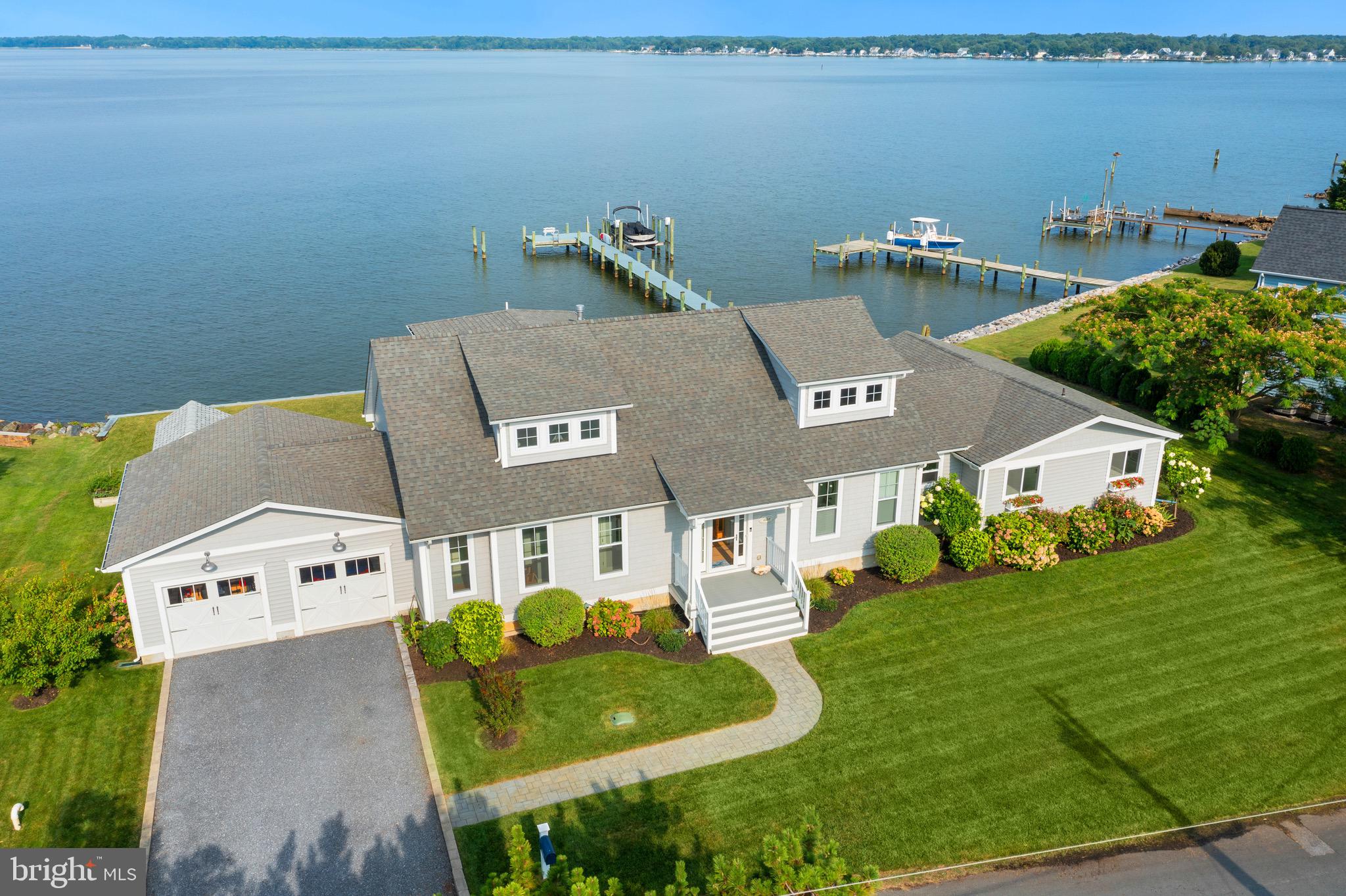 Welcome to this exquisite coastal-style home, a true gem that will captivate you from the moment you step through the front door. With 5 bedrooms, 3 1/2 baths, and an office, this custom-built residence offers a harmonious blend of modern luxury and natural beauty. Originally constructed in 2018, this home is the result of meticulous craftsmanship, as the original house was thoughtfully torn down and meticulously rebuilt. Enjoy breathtaking sunset views from the front door and wake up to picturesque sunrises at the back. The main level primary suite is a tranquil retreat, showcasing stunning river views. It boasts an oversized walk-in closet, a cozy gas fireplace, and a lavish en-suite bathroom complete with a walk-in shower. Step onto the wire scraped oak hardwood flooring that adorns the first level of the main house, setting the tone for a warm and inviting ambiance. The great room is a highlight, featuring vaulted, coffered ceilings, gas fireplace, and tasteful built-ins. Throughout the house, you'll notice custom interior doors, hardware and lighting that elevate the home's elegance. The chef's kitchen is a culinary enthusiast's dream, equipped with top-of-the-line appliances, including an induction range, and a convenient island with a built-in microwave and ice maker. A large walk-in pantry adds practicality and convenience to this culinary haven. Upstairs, you'll find an additional bedroom with painted sawn pine flooring, and an attached bathroom, showcasing a custom crafted antique vanity. There's also a bonus room, offering versatility as an office, dressing room, or extra sleeping quarters. A large butler's pantry and laundry room serve as a seamless connection between the main house and the charming original waterman's cottage. The cottage is a delightful addition to this property, offering 3 bedrooms, 1 full bathroom, and a cozy living area with a kitchenette - the perfect accommodation for visiting guests. Beyond its beauty, this home is designed to be energy efficient, boasting a conditioned crawl space accessible from the interior. Step out onto the spacious composite deck with cable railing at the back of the home and immerse yourself in the serene river views. The professionally landscaped grounds include a lawn irrigation system, enhancing the beauty of the property. A newer pier and bulkhead, along with an 8,000 lb. boat lift, ensure that you can make the most of waterfront living. Notably, this home is situated in a non-flood zone and offers a 4 ft MLW (buyer to verify). The 2-car garage with additional storage, as well as a shed, cater to your storage needs. Take advantage of the outdoor shower after a day on the Bay. No HOA restrictions mean that short-term rentals are allowed, adding an appealing dimension to this exceptional property. And all of this, offered at a price well below $2,000,000, makes it an unparalleled turn-key waterfront home in the area. Welcome to your dream home, where coastal charm, modern luxury, and waterfront living converge seamlessly. Don't miss this opportunity to make this piece of paradise your own.