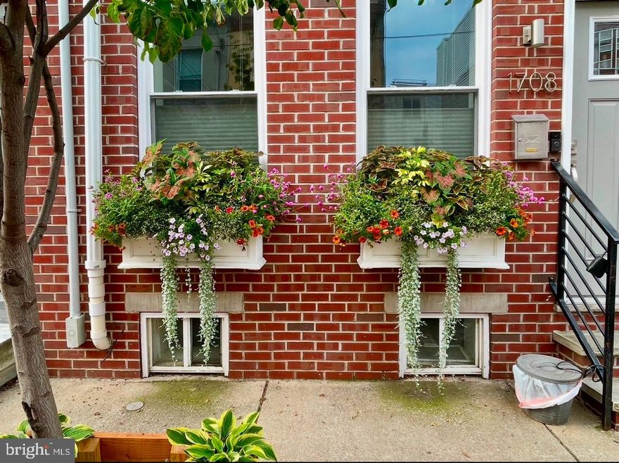 Classic Philly on the outside, yet new and modern on the inside, 1708 Latona St is a sunlit 3-story home that has been expertly rehabbed down to the studs, offering 3 bedrooms, 2.5 bathrooms, a private patio, and a roof deck. A low-traffic block leads to the red brick facade, where lively planter boxes and a vibrant blue door add charm. Inside, you'll find an open and airy main level with hardwood floors. A pair of windows brighten the living room, while the dining area has plenty of space to entertain. The showstopper is surely the gourmet kitchen, fitted with shaker cabinetry, stainless steel appliances, a center island with contrasting counters, a unique chevron backsplash, and breakfast bar seating. Convenient features include a custom pantry, a powder room, and a custom coat closet by the basement stairs. Out back, the fenced patio is the perfect spot for summer barbecues and laying out with a good book. Up on the second level, spacious bedrooms with hardwood floors and ceiling fans sit on opposite ends. At the center is a sleek full bathroom with a double vanity and a laundry closet. The third level is dedicated to the primary suite. There's a large bedroom with sliding doors that open to a balcony, a walk-in closet, and a full bathroom boasting a double vanity, a whirlpool soaking tub, and a glass-enclosed shower. Topping off the home is an expansive roof deck where you can hang out with family and friends while enjoying picturesque skyline views. If more living space is needed in the future, the basement is spacious with high ceilings, making it ideal for finishing. In addition to everything inside, this prime Point Breeze location earns a Walk Score of 90! Popular restaurants, local shops, and sprawling parks line the surrounding blocks, plus Washington Ave and Broad St are close by. Stores like Target, Sprouts Farmers Market, and Wine & Spirit are a short walk away, and neighboring East Passyunk has lots to explore. There's also easy access to public transit. Schedule your tour today!