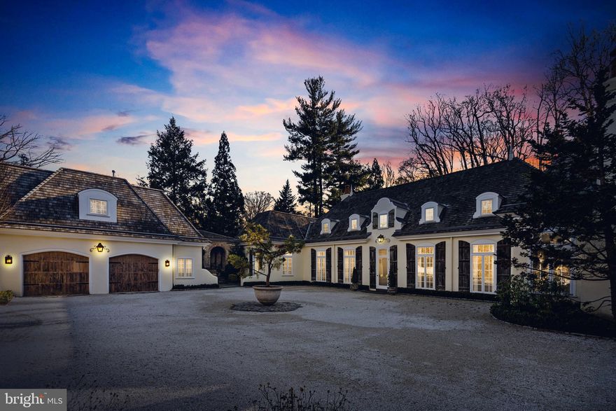 Welcome to 500 Rose Lane, located in the serene and picturesque Haverford Lower Merion Township. Situated on a sprawling 3-acre parcel of land, this magnificent home offers the perfect blend of privacy and luxury. As you approach the property, a winding drive leads you to a gravel courtyard, surrounded by meticulously maintained gardens.
The country French exterior of the home exudes charm, with rustic wood shutters and a cedar shake roof adding to its character. Step inside, and you'll be greeted by a grand entrance foyer with soaring 15-foot ceilings, adorned with floor-to-ceiling windows that flood the space with natural light. The transverse foyer seamlessly connects the various areas of the home.
The main living area is a testament to open concept design, encompassing a spacious dining room, living room, and library. Anchored by fireplaces on either end, this expansive area offers a warm and inviting atmosphere for gatherings and relaxation.
The sparkling white kitchen is a chef's dream, featuring slab marble counters, tall display and storage cabinetry, and top-of-the-line appliances. Adjacent to the kitchen is a cozy fireside family room and an octagonal breakfast room, providing a tranquil setting for casual meals and morning coffee.
The primary bedroom, conveniently located on the first level, is a true retreat. It boasts a generous sleeping room with its own fireplace, two ensuite baths, and multiple reach-in or walk-in closets. Connected to the primary bedroom is an intimate den/family room, also with a fireplace, which could easily be repurposed as an additional bedroom if desired.
One of the highlights of this home is its breathtaking views of the gardens from the main living area. Western-facing windows frame the lush greenery, creating a serene backdrop for everyday living. Step outside onto the expansive blue stone terrace, where you can bask in the beauty of the surroundings or take a refreshing dip in the inviting pool.
Upstairs, you'll find two generously sized guest suites, each with its own private marble bath and ample closet storage. These suites are ideal for accommodating guests for long-term stays, ensuring their comfort and privacy.
For added convenience, there is a separate suite located above the 2/3 car detached garage. This versatile space boasts high ceilings, a small wet bar with refrigeration, a large bedroom, a living area, and an attached bath.
In addition to its many features, the remarkable home at 500 Rose Lane boasts a captivating open-air covered stone loggia, reminiscent of the architecture found in the original estate. This enchanting space is accessible from both the courtyard and the rear and side gardens, further enhancing the seamless connection between indoor and outdoor living.
The stone loggia exudes elegance with its arches, creating a striking visual element and adding a touch of sophistication to the home. This inviting space serves as an exquisite entertaining area, perfect for hosting gatherings or simply relaxing while enjoying the beauty of the surrounding gardens.
Whether you choose to gather with friends for an evening cocktail party, savor a delightful al fresco meal, or simply unwind with a good book while surrounded by nature, the open-air covered stone loggia provides a versatile and captivating setting for memorable moments.
Immerse yourself in the enchanting ambiance of this elegant entertaining area, where the timeless charm of the original estate is seamlessly blended with modern luxury, making it a truly exceptional feature of 500 Rose Lane.