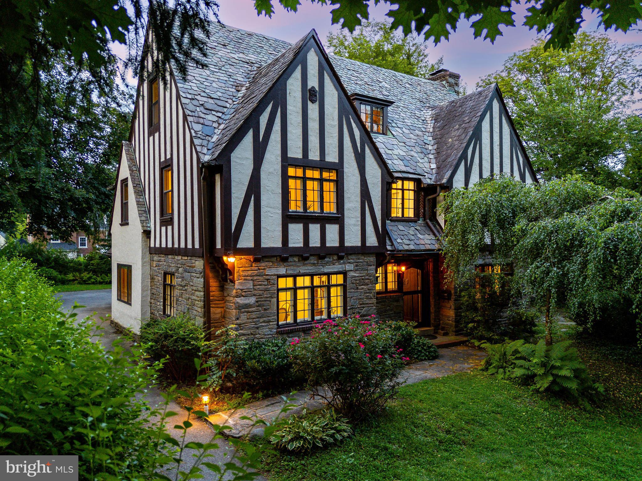 Set back from the street behind a sweeping lawn and mature trees, 1419 County Line Road is a rare offering: a Wallace & Warner-designed English Tudor where architectural integrity, historic detail, and modern convenience come together in perfect harmony.
Built in 1920 and cherished by its third owner for over four decades, this 6-bedroom, 3.5-bath home welcomes you with a curved arched front door, leaded glass, and original slate roof with copper gutters—a testament to the craftsmanship of the era. As you step inside, you’re immediately greeted by the warmth of hardwood floors and a gracious center hall floorplan that flows naturally from room to room.
To the right, the living room spans the depth of the house, filled with sunlight from large divided-light windows and anchored by a double-sided fireplace. French doors open to a flagstone-floor sunroom that feels like a secret garden lounge, ideal for morning coffee or evening unwinding.
To the left, the formal dining room features decorative molding setting the stage for holidays and special gatherings. The adjacent eat-in kitchen is outfitted with sleek updated cherry cabinetry, granite countertops, stainless steel appliances, and a family dining area overlooking the back patio. A convenient attached two-car garage completes this floor along with a powder room.
Upstairs, the primary suite features a large walk-in closet, and a luxurious oversized bathroom with rain shower. Three additional bedrooms share a large hall bath and large laundry room. The full height third floor offers two more bedrooms and a full bath beneath charming dormer ceilings—perfect for guest rooms, home offices, or creative studios and a lovely sitting area.
Throughout the home, you’ll find hidden treasures: ample storage closets, original hardware, and vintage wood details that speak to the home’s timeless soul.
The location couldn’t be more convenient. From your front door, you can walk 4 minutes to the Rosemont Regional train station and catch the R5, 5 minute walk Ashbridge Parks, easy access for 476, Bryn Mawr Film Institute, Mom's Market, La Colombe, Skirt and MORE. This is true walkable Main Line living, with easy access to top-ranked Lower Merion schools, Villanova University and three more nationally ranked colleges, and the award-winning Lower Merion Library.