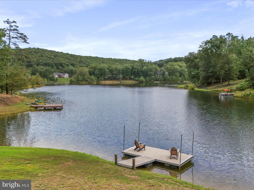 Rare find in this LAKEFRONT, like new home in Mineral County's premier Lakewood subdivision. One level living at its finest, this one owner custom-built home has all the upgraded features you want plus some you wouldn't have thought of! Walk with me as I guide you through this fabulous home. As you pull into the driveway, note the details of the stamped concrete front porch and the regal stone veneer. Step inside and note the 9' ceilings, a  welcoming foyer with a coat closet and take in from top to bottom the crown molding and the gleaming hardwood floors. Ah! Listen to the music coming from the great room's 7.1 surround sound speakers in the ceiling and walls. Appreciate the open floor plan of the kitchen opening into the great room and the kitchen upgrades of quartz countertops, pantry, maple custom cabinetry w/ soft close drawers, under cabinet lighting, glass tile backsplash, slide in electric stove, hardwood floors, pendant lighting above island, and breakfast bar seating,! The calming lakefront view is present from here, the great room, the dining area, the primary suite, the lower level family room and the garage! You'll love the memories made relaxing and entertaining on the 20' x 14' screened porch with shades, a TV hook-up and 2 outlets  that's attached to a 10'5" x 8' deck for grilling just off the kitchen! Main floor primary bedroom  w/ walk-in closet, tray ceiling, crown molding, hardwood floors, 5 windows (3 facing the lake!), recessed LED lighting, and hidden wall wire passage for tv! Primary bath features a soaking tub, tile floors, crown molding, double sink vanities, a walk-in shower, and lots of cabinetry! There's a second bedroom on this main level that's currently used as an office. A second full bath is present on the main level also! Did I mention the main level laundry off of the kitchen? What a step saver! The beautiful Levelor blinds will convey. The low E windows tilt in for easy cleaning! Total one level living for sure...but follow me to the lower level featuring 8'5" CEILINGS for more upgrades and surprises! The family room is WALK OUT LEVEL ,super spacious, complete with wet bar/mini fridge/microwave, a 9' pool table that conveys, TV hidden wire passage, and boasts the same surround sound system as the main level! With the 20' x 14' patio just outside, it's easy to picture holiday memories being made here! The 3rd bedroom is great for teens, grandkids, or guests and features comfy carpeting. The possible 4th bedroom is a good size, and wired for a theatre/multi-media room.  There is a storage room with convenient double doors to the outside and a utility room that completes this level.  If this isn't reason enough to knock your socks off, let me take you outside.  You have a floating dock!! It's 18' x 8'.  Also present is a canoe rack w/ 3 kayaks and 1 canoe to convey! Enjoy lakefront living and fishing in the stocked lake! Last but not least is a tour of the garage. Why? This is no ordinary garage! Begin w/ two ten foot insulated garage door with windows, 2 windows w/ lake view and a man door, cabinets and work bench, attic access with stairs, under cabinet lighting, LED ceiling lights , a 240 outlet, and a generous size of 25' wide by 23'6'.   FYI, tthe foundation is poured concrete , the hot water heater was replaced in March of '25, the refrigerator in '25, and the HVAC unit in '21 .The roof is 30 year architectural shingle. To summarize, this home  has been lovingly designed, meticulously maintained and if ever there was a home that says "Just move in and bring your toothbrush."  This is it! 4 offers in hand...sellers request highest and best and all final offers to be submitted by 5PM on Tuesday, 8/19/25.