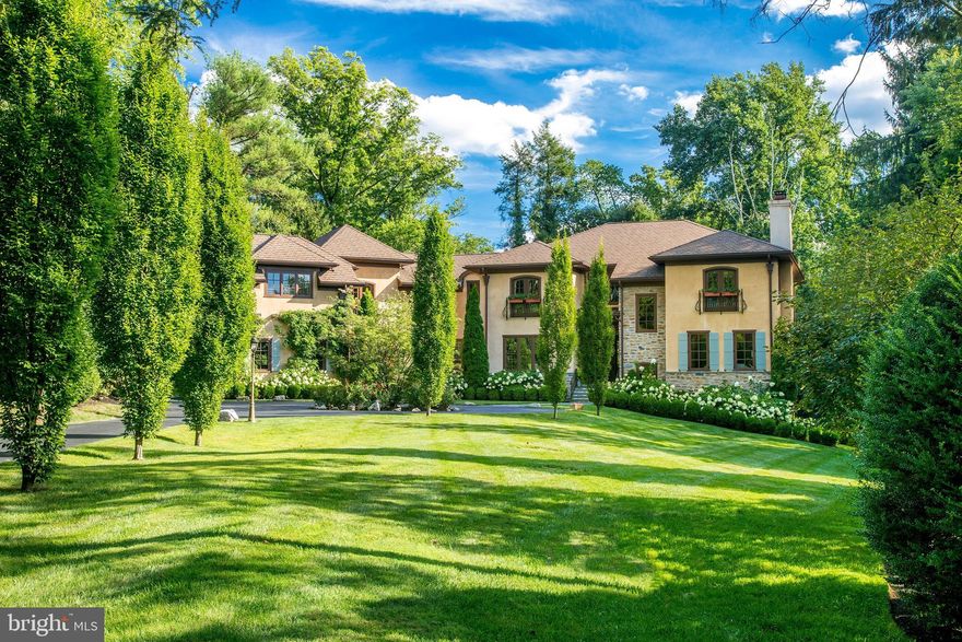 Nestled on over 1.5 acres of picturesque landscape, this custom-built Tuscan estate home showcases modern upgrades and luxurious features throughout. Accessed via a tree-lined driveway, the property exudes elegance and charm from the moment you arrive. Step inside to discover beautifully appointed interiors flooded with natural light, boasting grandly proportioned rooms and a highly desirable layout. Recent upgrades have elevated both the allure and functionality of the home, including the installation of new quartz countertops and backsplashes in the gourmet kitchen. Enhanced with Kountry Kraft cabinetry and updated hardware, the kitchen also features a refreshed island, perfect for casual dining or gathering. Throughout the residence, you'll find exquisite hardwood floors, exposed beams, oversized windows, and upgraded light fixtures that create a warm and inviting atmosphere. The main level offers a spacious family room with a stunning stone fireplace, ideal for casual enjoyment, while the adjacent dining room, complete with a wet bar, is perfect for hosting guests. Multiple decks, including a covered veranda and expansive lounge area with an outdoor fireplace, provide ample opportunities to enjoy the serene surroundings and entertain guests. Upstairs, the luxurious primary suite is a private retreat, featuring hardwood flooring, a gas fireplace, Juliet balcony, and his/her walk-in closets. The ensuite bathroom includes heated floors, and has been tastefully updated with new fixtures, adding to the home's modern appeal. Three additional bedrooms, each with its own ensuite bathroom, provide plenty of space and comfort for family and guests. One of them features a Juliet balcony and has a newer vanity with quartz countertops in its en-suite bathroom. At the end of the hallway, a versatile apartment-style suite offers endless possibilities. Featuring a bedroom, bathroom, home office, and den with fireplace, this space is perfect for multi-generational living or accommodating guests. The fully equipped kitchen and bonus room with built-in shelves provide added convenience and functionality. The finished lower level, designed for relaxation and recreation, is above ground and receives abundant natural light. Here, you'll find a spacious family room, perfect for gatherings and movie nights, alongside a game room and exercise area. A powder room adds convenience to the space, while a dedicated craft area with a sink provides a creative outlet for hobbies. The walk-out feature seamlessly blends indoor and outdoor living. Abundant storage is available. Additionally, two staircases allow convenient access to the lower level, enhancing its flow and accessibility. This fully geothermal home produces efficient heating and cooling. A tankless water heating system, heated floors in the kitchen, mudroom area, and guest-suite bathroom offer enhanced comfort and energy efficiency. A whole-home backup generator provides peace of mind, and synthetic exterior materials allow for minimal future maintenance. The storm water system is another bonus, as heavy rainwater drains into underground pits, preventing surface water flooding. There's a two-car garage with a 200 amp Tesla charging station, as well as an extra one-car garage, both giving inside access to the home. The grounds create a serene retreat, with ample space for outdoor activities and entertaining. Stone steps guide the way to a tranquil brook, accompanied by expansive newly landscaped grounds, offering a serene retreat. Furthermore, more than 25 trees were planted along a property line to enhance privacy. Ideally located in walking distance to the Village of Gladwyne, with scenic Bridlewild hiking trails steps from your door and the 87-acre Kenealy Nature Park close by, this home truly has it all - this home truly has it all - combining luxurious living with modern amenities in a idyllic setting.