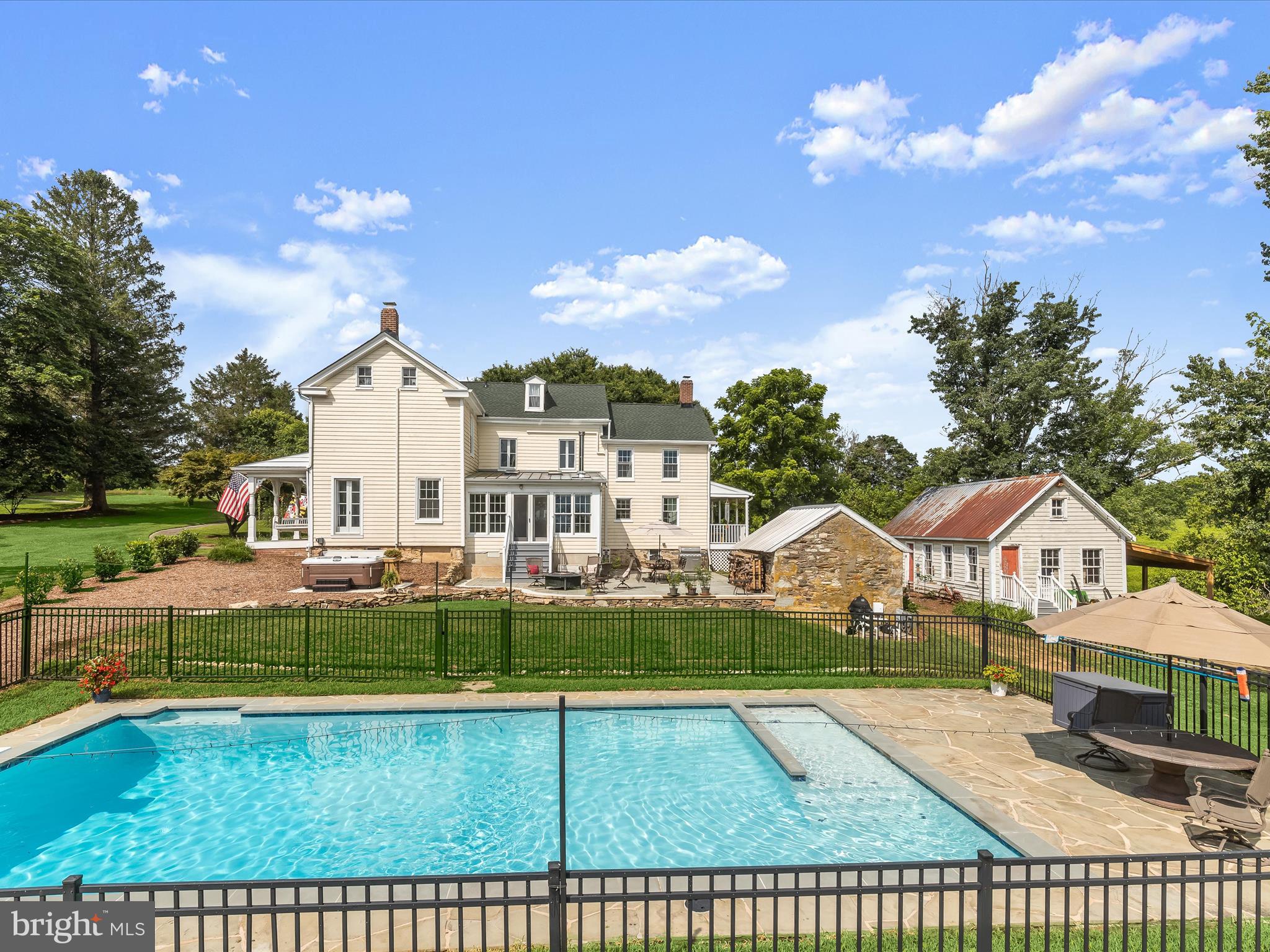 Nestled atop more than nine elevated acres in one of Monkton’s most coveted locations, this timeless mid-19th century farmhouse presents a truly rare opportunity to own a legacy property in the heart of North County. With sweeping views to the east, a secluded saltwater pool, and room to expand outdoor living spaces, this home seamlessly combines enduring character with thoughtful updates in a serene, storybook setting. Lovingly restored in the late 1990s and continually improved over the years, the home retains its historic soul while offering the comforts of modern living, replacement windows, standing-seam metal roofing, and a custom saltwater pool with bluestone patio and decking. A gracious front porch welcomes you inside, where the original center hall and staircase lead to sunlit formal living and dining rooms. A discreet powder room is tucked beneath the stairs, adding a functional touch to this classic layout. The north wing of the home embraces casual living with a country-style kitchen, cozy dining nook, dedicated laundry area, and a charming office nook. A warm and inviting family room addition with skylights, wood-burning stove, new carpet and freshly painted walls opens up to stunning views of rolling countryside and the pool beyond, perfect for everyday relaxation or weekend entertaining. Upstairs, choose from three distinct staircases, each marking a chapter in the home’s rich history. The upper level features a serene primary suite complete with a private bath and a cozy loft retreat reached by its own winder stairs. A lovely hall library bathed in natural light invites quiet moments and reflection. Three additional bedrooms, a shared full bath, and a loft-style fifth bedroom complete the second floor, offering flexible space for guests, family, or creative pursuits. The property itself, with its new split rail fencing, is equally captivating. Majestic shade trees dot the expansive lawn, bluestone patio, while a stone smokehouse and a framed shop building off the back porch offer charming utility or potential for future conversion. This exceptional property has been thoughtfully and extensively updated with a new architectural shingle roof, a lightning protection system, fully inspected and repointed chimneys, a new patio, and a resurfaced and retiled saltwater pool. Additional enhancements include a new water softener and treatment system, electrical service extended to the carriage house, smokehouse, and pool house, and the installation of a hot tub on a brand-new pad. Over 100 new trees have been planted, and comfort upgrades feature five mini-split systems, new AC and heat pumps, and full-house insulation. The kitchen has been refreshed with a new refrigerator, microwave, and stove (2023), alongside a new washer and dryer (2023) and water heater (2023). A new circular driveway adds both convenience and curb appeal, rounding out the impressive list of improvements made to this remarkable home. Beyond, the additional acreage includes remnants of a barn foundation and an old spring house, ideal for creating pastureland, gardens, or even a guest cottage. Located minutes from the Gunpowder River and the NCR Hike & Bike Trail, this home is perfectly positioned to enjoy the best of the North County lifestyle. Explore nearby breweries, wineries, shops, and restaurants, or make a quick trip to Hunt Valley for additional conveniences. Commuting is simple via I-83, and the property lies within the highly rated Hereford Zone school district. Whether you're searching for a private retreat, a historic homestead, or a once-in-a-lifetime place to write your own chapter. **Please note Lot lines are incorrect in zillow. This is almost a 10 acre property. Please refer to photo of plat map in with the photos.**
