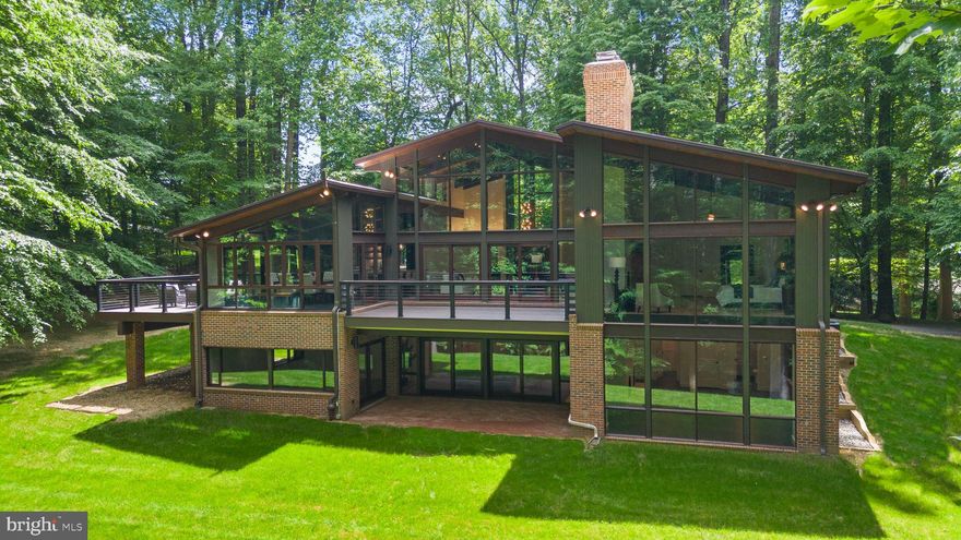 Introducing this meticulously renovated mid-century modern masterpiece where every detail has been thoughtfully crafted to offer unmatched luxury and style.  Nestled on a serene 5-acres, this home combines the tranquility of a private retreat with the convenience of urban proximity. Every detail of this Acorn Deck house exudes sophistication and quality.
Step inside to be greeted by soaring 23-foot cathedral ceilings and an expansive living room bathed in natural light, courtesy of walls of windows. Sliding doors open to a stunning, maintenance free deck, seamlessly blending indoor and outdoor living.   The refinished hardwood floors and planked ceilings complement the two story, double-sided fireplace, showcasing the home’s exquisite craftsmanship.  
The state-of-the-art kitchen features an open-concept design creating a seamless flow between the living room, kitchen and dining room.  An oversized island provides a central gathering point, perfect for entertaining.  The kitchen and dining room boast heated ceramic tile floors, ensuring comfort and warmth. Large skylights and oversized windows awash the space with natural light, enhancing its inviting ambiance.  
The luxury owner’s suite is a private sanctuary, with walls of windows, a double-sided arched fireplace and massive walk-in closet.  The owner’s spa-like bathroom is adorned with vaulted ceilings, a free-standing soaking tub, frameless glass shower with multiple shower heads, and double vanity, all with breathtaking views of the surrounding forest.
The lower level offers a generously sized family room with dual-sided wood burning fireplace and 2 large sliding glass doors leading to a covered patio.  This level also includes an expansive en-suite bedroom with fireplace, sliding glass door to the patio and a bathroom featuring heated floors, single vanity and large shower.  The second bedroom provides private access to a shared hall bathroom, which boasts a double vanity and a huge walk-in shower with three rain shower heads.  The third bedroom also features a sliding glass door to the patio. All three bedrooms come with ceiling fans and walk-in closets.
Additional features of the property include a detached brick garage with attic space, offers potential for a home office or studio.  This home is more than just a residence; it’s an artful expression of modern design harmonizing with nature.  Experience the unmatched beauty and luxury of this remarkable property. Schedule your private tour today and discover the lifestyle that awaits you.