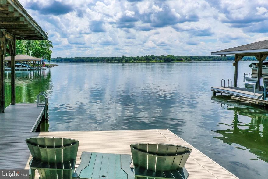 Exceptional value on this beautiful waterfront estate nestled on the public side of Lake Anna, Virginia. Great location with deep, clean water and high-speed Xfinity Comcast internet. Spanning over 4,800 finished square feet spread out over three levels, with 5 bedrooms—including two primary suites—and 4.5 baths. The open-concept layout is highlighted by a grand two-story great room with a cozy gas fireplace and stunning custom wide-plank hickory hardwood flooring throughout the main level. The gourmet kitchen is a showstopper, complete with sleek granite counters, black stainless appliances, a 5-burner gas stove, wall oven, and a massive center island illuminated by stylish pendant lights. The lakeside main-level primary ensuite has a walk-in closet, jetted tub, separate tile shower, and doors to the back deck. Upstairs, your family and guests will enjoy 4 bedrooms and 2 full baths. The finished walkout lower level is designed for entertaining and relaxing, offering a generous family room, living room, recreation area, wet bar, full bath, storage, and a wall of 16-foot glass doors that open to a serene concrete patio. Outside, your personal paradise awaits: a covered boathouse with maintenance-free decking, electric lift, sundeck, jet ski pad, and 8+ feet of deep water off the dock. Enjoy 146 feet of pristine shoreline and a stone bulkhead already in place. The park-like yard is spacious and perfect for outdoor games and entertaining.  You'll also appreciate the convenience of having a washer and dryer on both the main and lower levels. Nestled on a 1-acre lot with a park-like setting, gorgeous views, a paved driveway, 2-car attached garage, tankless water heater, invisible dog fence with 2 collars, 12x26 shed with a roll-up door and its own electric panel and service, 50 AMP RV hookup, 4 lake-fed water spigots, and so much more! Come see why this home is the ultimate Lake Anna retreat!