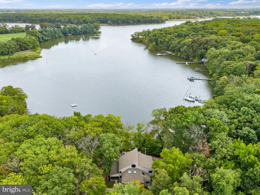 Private Eastern Shore Waterfront Retreat

Tucked away on a serene, wooded 5-acre waterfront peninsula, 6581 Elizabeth’s Lane offers an unparalleled private escape on West Fork Langford Creek, feeding into the Chester River. With over 1,000 feet of deep water shoreline and three sides of water frontage, this secluded retreat provides easy access by boat to Rock Hall, Kent Island, Annapolis, and St. Michaels. Outdoor amenities include private walking trails, a tennis court, a horseshoe pit, and a cozy fire pit area, making it a haven for relaxation and recreation.

The home's beautiful wood siding blends seamlessly with the natural surroundings, enhancing its charm and character. Enter through the welcoming front porch into the foyer, which leads to a grand two-story great room, where expansive casement windows and sliding doors frame breathtaking water views.
Inside, vaulted ceilings with exposed wooden beams and intricate craftsmanship add warmth and elegance, while a cozy reading nook with a European-style wood stove provides the perfect place to unwind. Designed for entertaining, the spacious kitchen features Corian countertops, a large center island, a Sub-Zero refrigerator, a Viking gas range, and a wet bar with beverage refrigerator and built-in ice maker. A screened-in porch off the kitchen provides the perfect setting for crab feasts and outdoor dining, all while enjoying the tranquil water views. A laundry room off the kitchen adds convenience. The main-level primary suite is a true retreat, boasting stunning water views, a private sitting area, custom closets, and an ensuite bath with a vaulted ceiling, jetted soaking tub, and double vanity. Upstairs, four additional bedrooms—all with water views—feature charming loft spaces. A second laundry room, a full bathroom, and a spacious cedar hall closet add to the upper level’s functionality. The open landing overlooks the great room, offering panoramic views of the water. The large, unfinished basement presents endless possibilities and ample storage. Outdoor living is perfectly designed for waterfront enjoyment, with an expansive wraparound deck with built-in bench seating. 

A private trail leads to the dock, which is equipped with lights, electricity, two slips and manual lifts. Thoughtfully designed trails wind through the property, guiding you along scenic wooden paths to the fire pit area, the tip of the private peninsula, or steps leading to the water’s edge. Located within an easy drive to Philadelphia, Annapolis, Wilmington, and Washington, D.C., this exceptional property is ideal as a full-time residence or a weekend getaway. Experience the beauty and tranquility of Eastern Shore waterfront living at its finest.