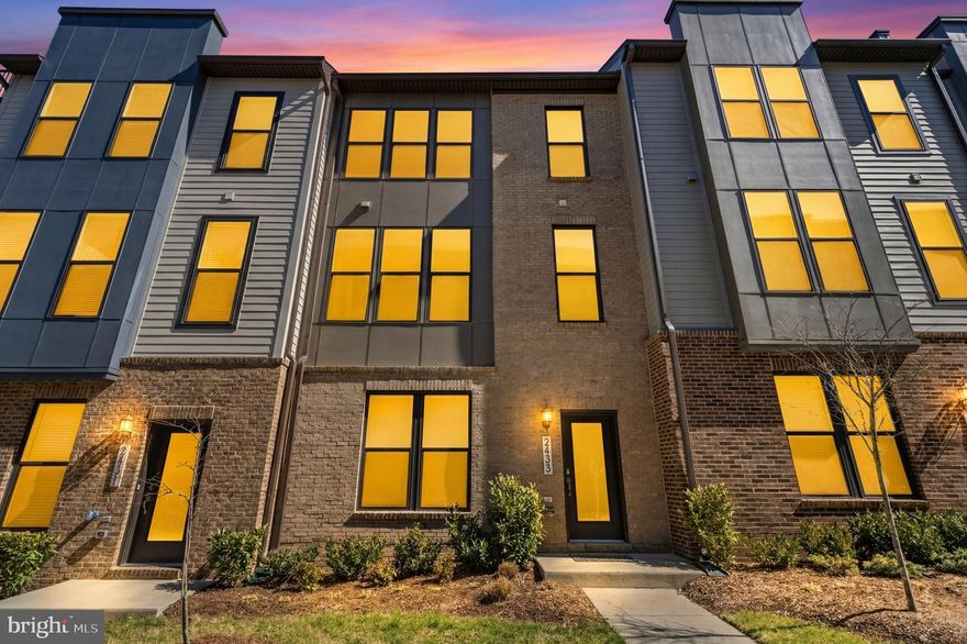 Welcome to this stunning brick front 3-bedroom, 2 full and 2 half bath townhome built by Stanley Martin, less than 4 years young and meticulously upgraded throughout. Featuring 10-foot ceilings and Chesapeake All-American laminate flooring in Century Oak on all three levels, this home offers a modern, cohesive feel. Abundant natural light pours in through oversized 7-foot windows, all fitted with cordless top-down/bottom-up honeycomb shades.

The entry level welcomes you with a spacious recreation room, convenient half bath, and access to the 2-car garage complete with an epoxy flake floor—both durable and stylish, and perfect for a home gym or additional workspace.

The main living level is designed for both everyday living and entertaining, featuring recessed lighting and an open layout filled with natural light. The gourmet kitchen is the centerpiece, showcasing white cabinetry, quartz countertops, stainless steel appliances, a flat surface electric cooktop, double oven, pantry, and a built-in work nook. The oversized 12-foot island comfortably seats four and includes a sink, making it ideal for gathering and conversation. The living room features a built-in electric fireplace and access to the deck, while the dining area provides the perfect setting for entertaining. A powder room completes this level.

Upstairs, you’ll find three bedrooms, including a spacious primary suite with recessed lighting and two walk-in closets. The luxurious primary bath offers double vanities, a private water closet, and an oversized shower. A full hall bath and full-size washer and dryer with additional shelving add convenience.

Location truly sets this home apart—just minutes to the Innovation Center Metro, Dulles Airport, shopping, dining, grocery stores, and Dulles South Recreation & Community Center.