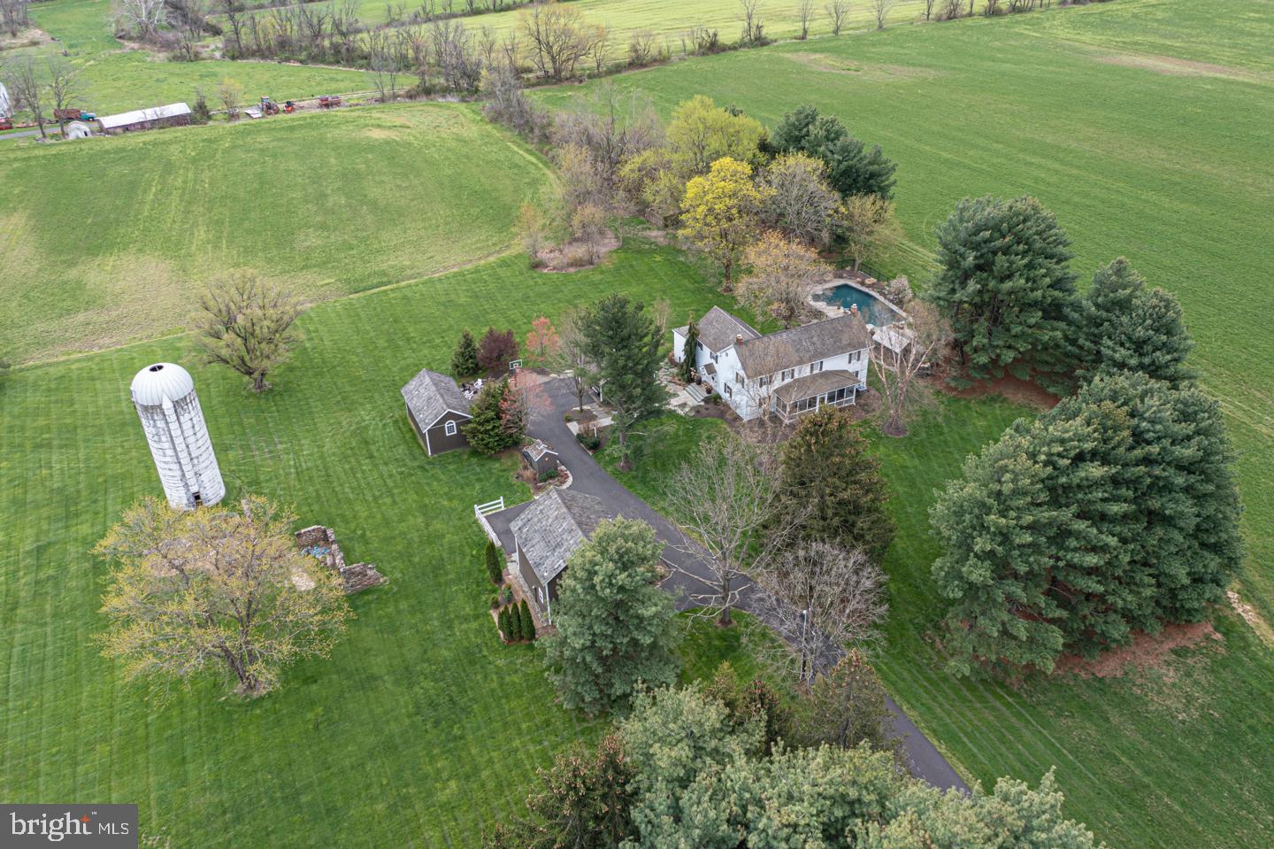 Set on over 5 acres in the heart of Bucks County, this circa 1780 farmhouse was completely remodeled in 2020 and is the perfect blend of function and beauty with authentic antique charm and character at every turn. A long driveway leads to this homestead, surrounded by 200+ protected acres of farmland. In addition to the main house, a carriage house, several out-buildings, a picturesque silo and stone ruins grace the property. Completely updated and lovingly maintained, the character of the original home is undiminished. Large rooms, stunning wide plank floors, deep sills, plaster walls and exposed beams are thoughtfully woven in throughout the home in a stylish and inviting manner. The heart of this home is the exquisitely remodeled and chic kitchen with Carrera marble countertops, Wolf double wall ovens and induction cooktop, Sub Zero refrigerator and a large center island. The sunny breakfast area provides views of the wooded backdrop and easy access to the deck for alfresco dining and entertaining. The gathering room with exposed beams is bright and open to the kitchen. The formal living room boasts a stone fireplace with wood burning insert with a reclaimed wood mantle and the dining room with original built-in’s and restored pumpkin pine floors is ready to host the next holiday celebration. Completing the main floor is an updated half bath, cozy den that would make an ideal workspace and a screened-in front porch. Upstairs, a stylish main bedroom with chic barn door entry offers a large walk-in closet and beautifully marble tiled bath. Three other spacious bedrooms share a newly remodeled bath. An unfinished attic space provides wonderful storage. Outside, surrounded by beautiful landscaping filled with flowering shrubs, is the short walkway leading to the crystal blue pool that creates a personal oasis to entertain or relax. The carriage home, also completely remodeled in 2010, offers unlimited possibilities such as office space or flex space that includes bonus room, full bath and an amazing loft with a vaulted ceiling and exposed beams. Quaint features such as the original brick porch have been maintained while incorporating modern elements such as a new foundation, spray foam insulation and split heating/cooling system installed in 2020. The original well house, now used as a potting shed, was restored to add charm to the property. A barn, built in 2012, is heated and offers wonderful storage and/or workspace for any car enthusiast or hobbyist. A two car detached covered garage offers additional parking. Additional home amenities include central air, New driveway, New well pump, New water holding tank and New gutters on the main home. Nestled among trees and nature, there is no shortage of space for either hosting guests or relaxing outside in a private, peaceful and picturesque Bucks County setting. All found in the much desired Central Bucks School District, this charming property is the perfect respite.