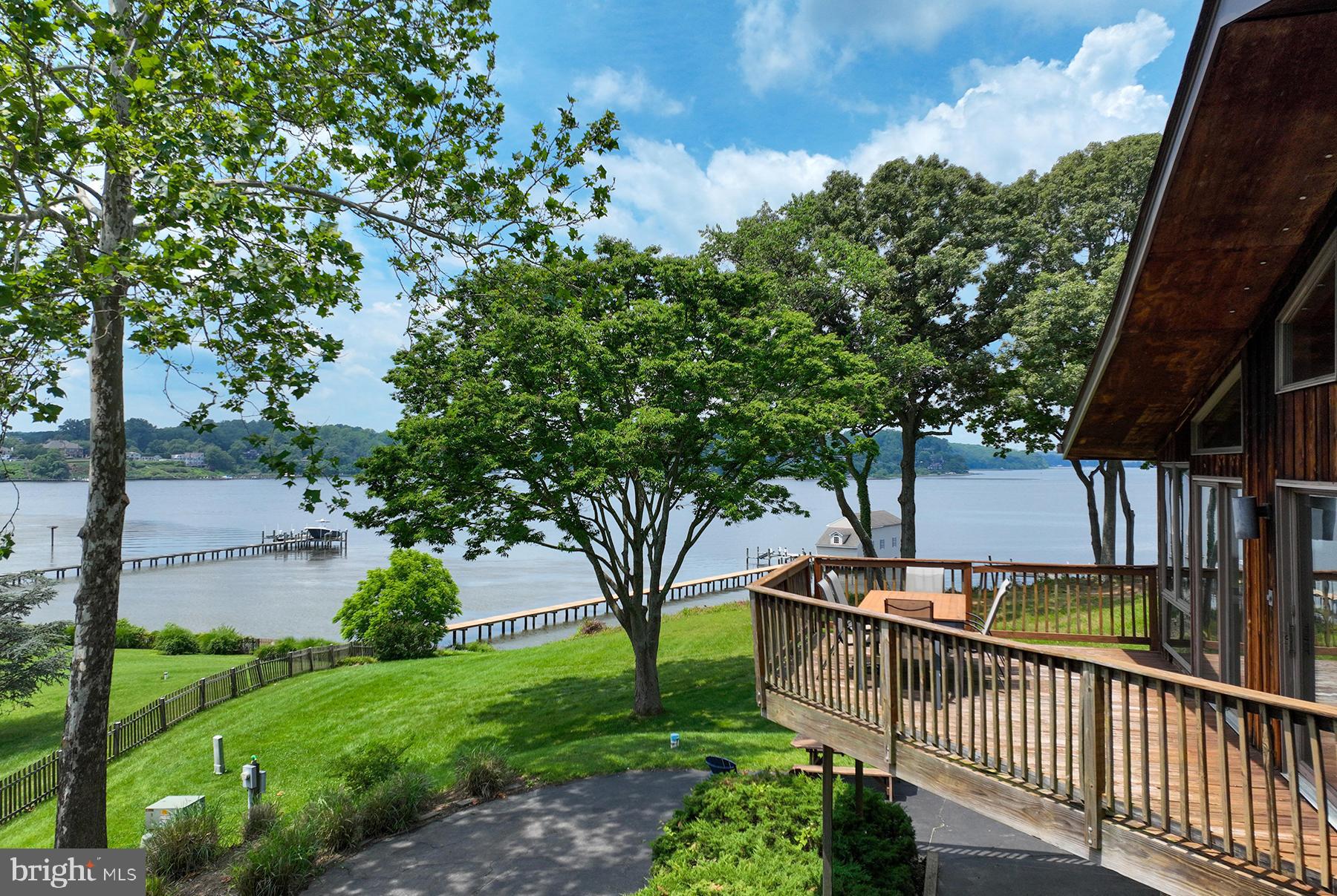 296 W Joyce Lane is a truly spectacular and unique waterfront opportunity on the Severn River. The history and charm of the location set it apart from the competition and the sprawling lot with mature landscaping, private pier, and HUGE Severn River views make it a one-of-a-kind property. With a desirable Western exposure, sunset will become the favorite part of the day. The possibilities are endless with this 1+ acre lot and 4-bedroom, 3 full bathroom home.
One of the things that makes this home really stand out is the approach, not only to the home but also into the community. As you drive under the old train tracks and past the lush acres and horse pastures, you immediately sense the unique charm and serene feel of the community. Just a short distance from the home, these train tracks dropped passengers off to finish their destination by ferry. Now, the tracks have become part of the Baltimore and Annapolis (B & A) biking and hiking trail. The tree-lined approach to the home opens to wide vistas of the Severn River. A gentle stroll to the water’s edge leads to a spacious, level yard that is a perfect spot for playing games or setting up chairs to relax and enjoy the stunning views. Boating, fishing, crabbing or even swimming are easy outdoor adventures from the expansive private pier. With BIG views up and down the Severn River, the pier offers an ongoing invitation to enjoy the Chesapeake Bay breeze blowing up-river and breathtaking views.
The home is spacious and bright with so many opportunities for the next owner to make it their own. The main living space has walls of windows facing the water, a wood-burning fireplace, and access to one of the waterside decks. Up a few steps, the kitchen has room for a dining table and direct access to a second waterside deck. Down the hall there is a library with wood-burning fireplace. The primary bedroom suite, with private bathroom, has Severn River views and sliding glass doors to the waterside deck and yard. There are two more bedrooms and a full bathroom on this level. The walk-out, lower level of the home has a fourth bedroom with water views and a full bathroom. There’s also a large utility room that offers additional storage space. The attached one-car garage is accessible from this level.
This very special property has brought such joy to one family for more than 40 years, but it is now time for a new resident to create memories…take advantage of this incredible opportunity to renovate the existing home or plan your dream house. Schools include Severna Park High, Severna Park Middle, and Jones Elementary. Although it is a short drive to major commute routes (Rte 2 and Rte 50), the drive into the community really makes you feel very distant from city life. This is the spot to come and relax!