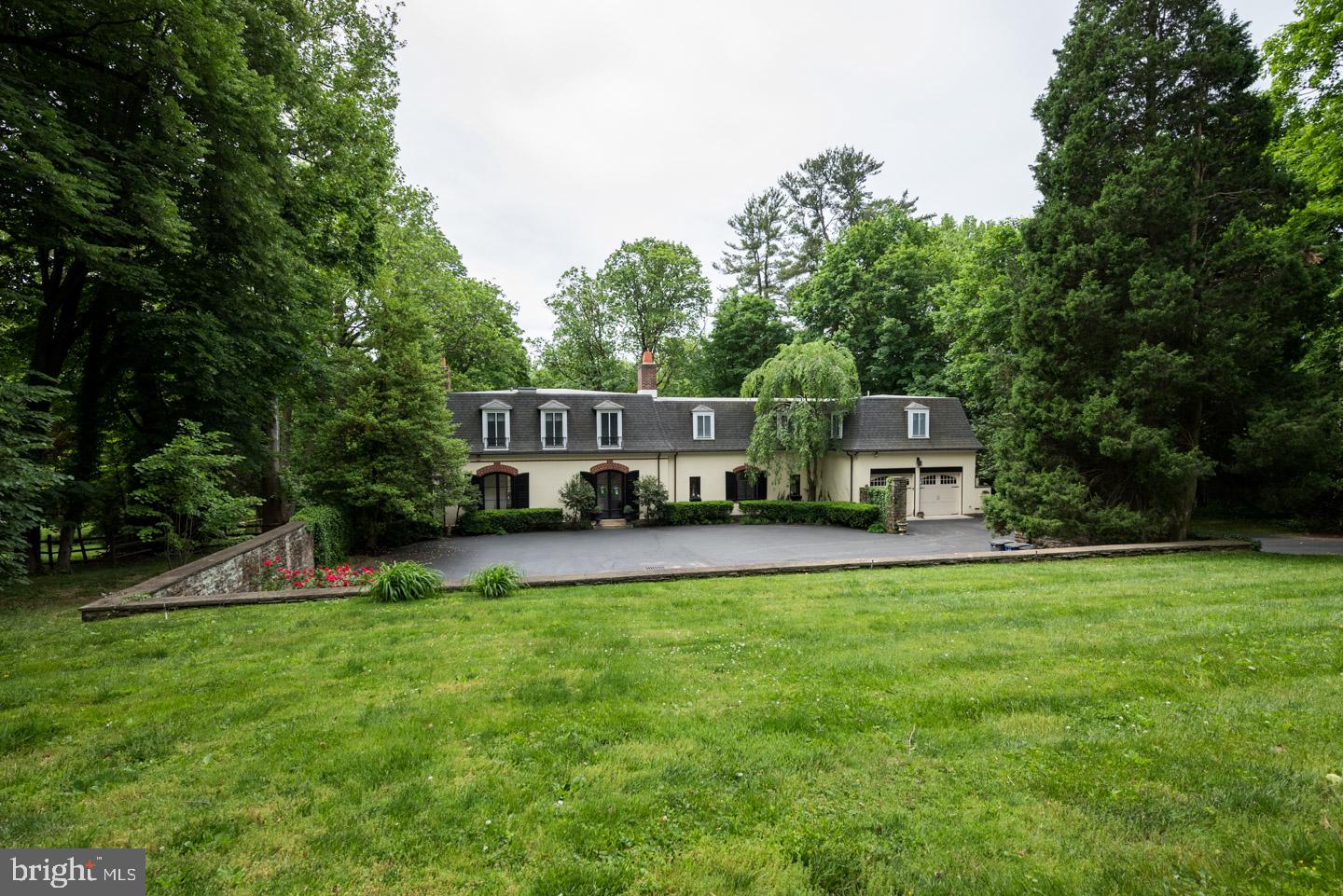 This one-of-a-kind estate offers a graceful combination of high-end, contemporary elements and timeless, elegant detail characteristic of this distinctive French architectural style home. A double-door entry leads to the spacious foyer, with turned staircase and gorgeous iron and wood railing. Continue through the foyer and step down through an arched doorway into the sunken Living Room which will amaze, with magnificent parquet floors, oversized double arched windows, floor to ceiling built-ins that run the width of the room, crown molding, fireplace, and double glass doors opening to the slate patio overlooking the natural landscape included with this estate. Flow into the formal dining room with another crystal chandelier and two sets of double glass doors providing gorgeous lighting and leading to both Patio and Sunroom, perfect for overflow of guests. At the center of this home is the impressive Kitchen, which leaves nothing to be desired. Its features include granite counters and stainless-steel appliances, built-in refrigerator, a 2-tier granite island with double sink and counter seating, custom tile backsplash, recessed lighting, 6-burner Viking range with griddle and hood, lighted glass pane cabinets with undermount lighting, crown molding, double wine chiller, warming drawer, and ample space for a dining table and/or seating area. Perfectly placed around the corner is the Butler's pantry, with granite counter and glass pane cabinets. From the kitchen, step down to the inspiring Sunroom, with built-in lighting and ceiling fans, and convenient sink/wet bar. The possibilities are endless for this brilliant space. Off the kitchen is the Family Room with convenient access to a covered patio. On this level you'll also find a convenient organizational space off the entryway which leads to a newly renovated powder room for the main level. On the second level, you will find 5 generously sized bedrooms, and 4 full bathrooms, including a Jack & Jill with double vanity and steam shower, and 3 additional en-suite bathrooms. The Master Bedroom features a fireplace, built-ins, and a dressing area leading to the Master Bath with skylight. This home boasts a full basement with endless possibilities for additional living space in the future. 1.5 acres of land surround this unique home, and an unmistakable highlight is the private yard with large open space leading to the in-ground pool; the perfect place to entertain, unwind, and enjoy nature. Close to everything this area has to offer, all of Philadelphia’s renowned suburbs, and within walking distance to the Villanova Station & Amtrak, providing easy access to New York. Be sure to view the detailed Floor Planning & Virtual Tour and schedule a showing of this magnificent home today!