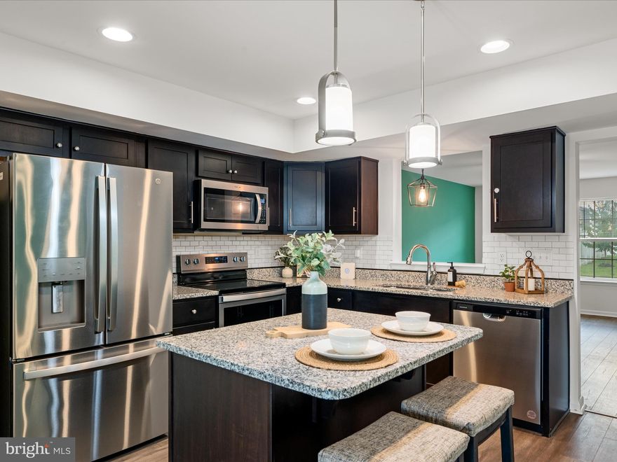 Freshly painted & move-in ready end-unit townhome in a conveniently located community! Featuring a fenced yard with stamped concrete patio that backs to open land, enjoy quiet comfort in your own private space while living within walking distance to lots of shops and restaurants. The main level features an open-concept layout with an eat-in kitchen equipped with granite countertops, a center island with seating, and a beautiful tile backsplash. The kitchen flows seamlessly into the ample-sized family room with adjacent half bath. Luxury vinyl plank flooring extends throughout the main level, while brand new carpeting adds a comfortable feel to all 3 bedrooms and the staircase. Upstairs, the primary suite includes a walk-in closet and an ensuite bath with a dual vanity and linen closet. Two additional bedrooms, including one with a stylish accent wall, share another full bath. The upstairs laundry area makes for an efficient flow that improves daily life.  With easy access to major commuter routes and local amenities, make this one yours and call it "home!" Also makes a great rental property for a saavy investor!