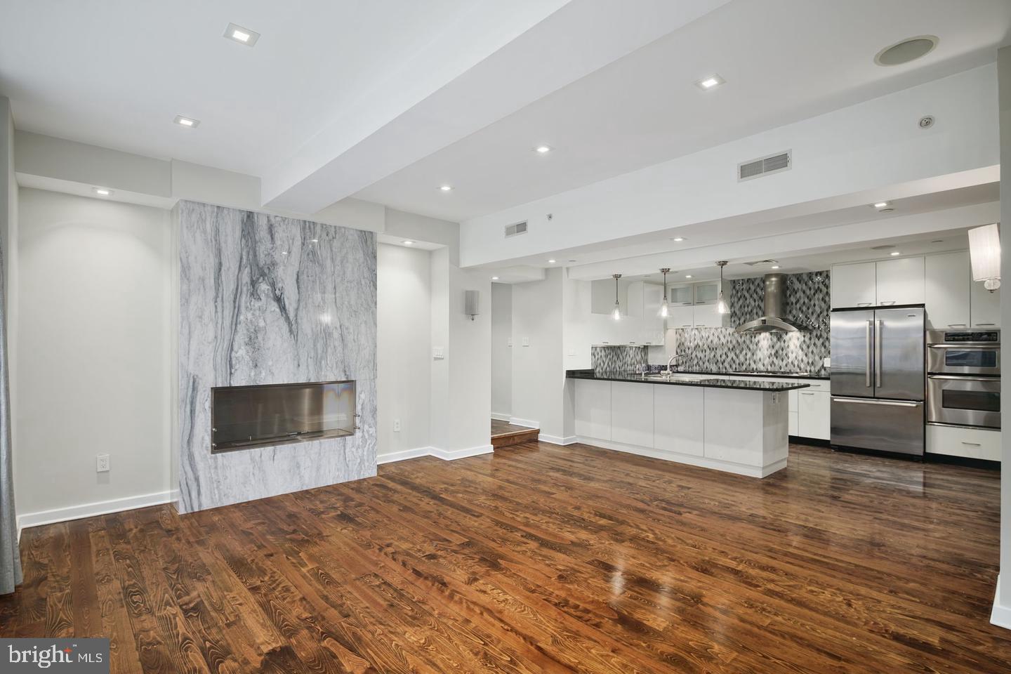 RITTENHOUSE living at its best. Enjoy space, comfort, and privacy in this elegant and updated two-bedroom corner unit. Located right across the street from Di Bruno Brothers and just two blocks from the Square, this nearly 1,800-square-foot property is designed with significant natural light and numerous upgrades. Enter through the foyer with a view of the dining room and a wall of windows adorned with custom silk drapery. Continue to the open-concept living room and kitchen, all featuring hardwood floors. Cooks will love the chef’s kitchen, which contains high-end stainless-steel appliances, natural stone countertops, ample cabinet and prep space, a breakfast bar, and a spacious walk-in butler's pantry. The living room offers a large, comfortable seating area complete with a custom gas fireplace encased in floor-to-ceiling marble. Adjacent to the living room is a dining area with a custom dry bar and wine fridge - perfect for entertaining. Primary and guest suites are located at opposite ends of the home, ensuring maximum privacy for you and your guests. Each room features an updated designer en suite full bath. The primary suite, boasting three large windows, wall-to-wall carpeting, and a Phillip Jeffries wall covering, is spacious enough to accommodate a king-sized bed. It includes a large walk-in custom-designed closet and a separate closet for the washer and dryer. The bath area has a deep soaking tub, a rainfall shower with glass enclosure, and a long, quartz-topped vanity with two sinks. The guest suite has hardwood floors, a custom built-in desk and bookshelf, and a bathroom that can be accessed from both the main hall and the guest room. It also has abundant and custom built-in storage and custom lighting. There is an additional room located across the hall with floor-to-ceiling custom cabinetry and a built-in desk that is perfect for additional storage or a separate home office. Tech upgrades include energy-efficient LED lighting throughout, a Sonos sound system with hard-wired speakers, and a Nest learning thermostat. New HVAC in 2021. No more than two units per floor, newly renovated elevators and lobby, and a video intercom system and secure keycard access to the building and elevators. This beautiful property is just steps away from everything Center City has to offer.