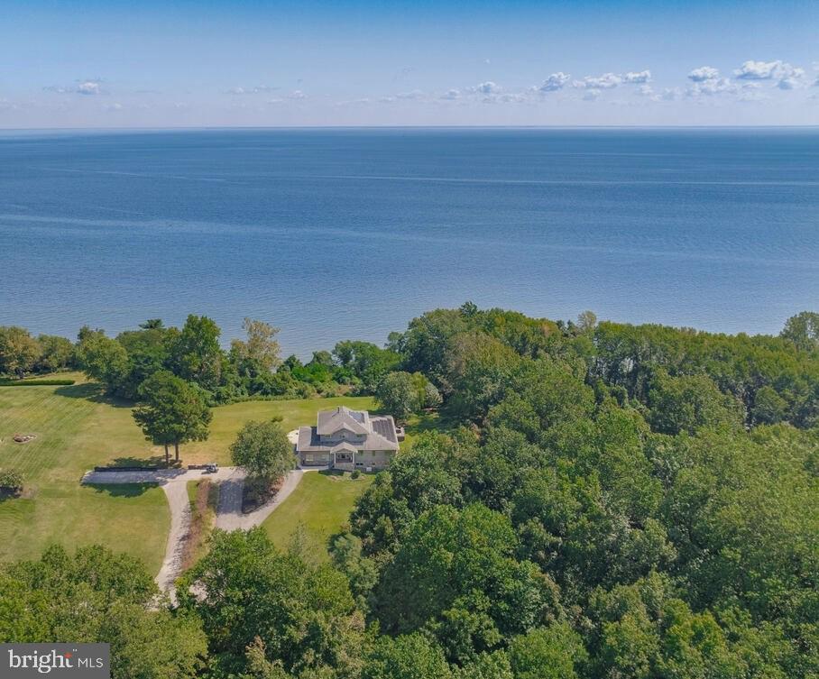 Wake up each day to SWEEPING VIEWS of the Chesapeake Bay, where the sun rises over the horizon, boats drift across the water, and the Eastern Shore shimmers in the distance. This extraordinary custom-built home offers more than 6,700 square feet of luxurious living space, thoughtfully designed for comfort with a FIRST FLOOR PRIMARY SUITE , casual elegance, and energy efficiency. FULLY-OWNED SOLAR PANELS and five Tesla PowerWalls keep energy costs remarkably low, while the private 1.3-acre setting—tucked at the end of a quiet road within an enclave of three other luxury homes—provides peace, seclusion, and preserved wooded surroundings. ** Step inside to a grand foyer with authentic WALNUT HARDWOOD FLOORS, craftsman-style custom millwork, and an elegant staircase. The SPACIOUS GREAT ROOM showcases a SOARING COFFERED CEILING, clerestory windows, and a cozy wood stove. ** For those who love to cook and entertain, the GOURMET KITCHEN boasts extensive cherry cabinetry, a large ISLAND WITH SEATING, a GIANT-SIZED PANTRY, and PREMIUM APPLIANCES, including dual refrigerators, double ovens, and a six-burner gas cooktop. The adjoining dining room is framed by UNFORGETTABLE BAY VIEWS through a wall of windows rising to the vaulted ceiling. ** Indoor-outdoor living comes easy with a SCREENED PORCH designed to serve as an outdoor kitchen, plus an all-season SUNROOM and adjacent DECK--all offering different vantage points to enjoy the views. ** The main-level PRIMARY SUITE is a true retreat, opening directly to the sunroom and bay views. Its spa-like bath features dual vanities, a large walk-in shower, and an oversized DRESSING-ROOM CLOSET, while a second walk-in closet and super-sized laundry room complete the primary wing. ** A flexible HOME OFFICE with a closet could also serve as another first-floor bedroom. ** Additional highlights include a mudroom/drop-zone with built-in storage and access to the over-sized three-car garage, which has two EV charging ports and high ceilings that can accomodate a lift and abundant storage. ** Upstairs, a LOFT overlooks the foyer, and THREE ADDITIONAL BEDROOMS—ALL WITH BAY VIEWS—share a beautifully appointed bath. ** The lower level expands the living space with YET ANOTHER BEDROOM, full bath, SEVERAL RECREATION ROOMS, THEATER ROOM, wine cellar, and storage. An EXPANSIVE semi-finished room, with large windows and level-walkout doors, is ideal for a gym, studio, or workshop. ** Outside, along with the views, you'll enjoy the lush landscaping, a koi pond with waterfall, patio, irrigation system, and large garden shed ** For those seeking more acreage, the ADJACENT 1.18-acre CLEARED AND BUILDABLE LOT IS ALSO AVAILABLE FOR PURCHASE. ** Located in Huntingtown with TOP-RATED SCHOOLS and an easy commute to D.C. and Annapolis, this one-of-a-kind property offers breathtaking views, refined finishes, and unmatched energy efficiency—an exceptional retreat to call home.