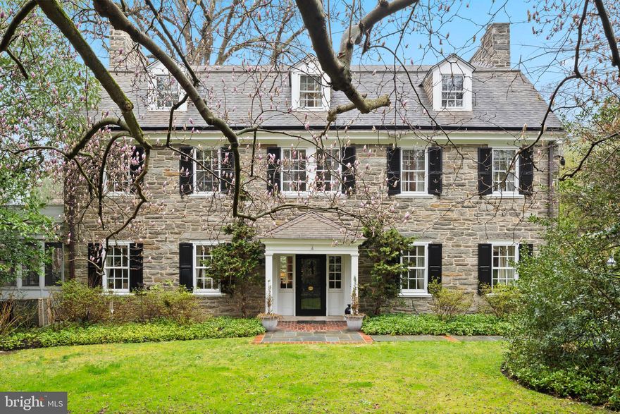 Nestled along West Bells Mill Road near the entrance to Forbidden Drive sits this timeless center hall colonial that offers a blend of historic charm and modern comfort. Surrounded by mature trees, lush gardens, and wildlife, this home feels like a private retreat while remaining conveniently close to vibrant shopping and dining options in Chestnut Hill. A Dutch door welcomes you into the gracious center hall, where original, random-width hardwood floors set the tone for the home’s enduring elegance. At the rear, a second Dutch door opens to a beautifully designed slate patio, gracefully shaded by a mature canopy tree and framed by lush, thoughtfully curated gardens—an inviting outdoor room ideal for quiet reflection or effortless entertaining. The inviting living room features a wood-burning fireplace with a granite mantel, crown molding with picture rails, and a bay window flanked by custom built-ins. French doors lead to a charming screened porch with a brick floor and access to the patio. Original glass-paned French doors open to the formal dining room, showcasing classic wainscoting, a fireplace with stone mantel, and a beautiful arched built-in. A cozy den with built-in bookshelves and adjoining powder room offers a comfortable spot for reading or unwinding. The thoughtfully updated kitchen features granite countertops, custom cabinetry, a large center island with Wolf range, and a vaulted, beamed ceiling. High-end appliances include Viking double ovens, a Miele dishwasher, and a paneled refrigerator. The kitchen offers access to the patio, while a charming vestibule connects to the driveway—providing convenient everyday entry for family and friends alike. Adjacent to the kitchen, the original butler’s pantry adds character and functionality, with glass-front cabinetry, a hammered copper sink, and second dishwasher, and access to the rear staircase. The grand staircase leads to a spacious landing with a large bay window provides a peaceful vantage point over the rear patio. The hallway includes custom built-ins and leads to the study. The light-filled primary bedroom features a wood-burning fireplace, built-ins, and full bath. Two additional bedrooms share a walk-through bathroom, while a separate bedroom suite includes generous closet space and a private full bath. The laundry room offers ample storage space and the original Stiffel & Freeman safe. The expansive third floor includes a very large room with built-ins and abundant storage which is perfect for a play room, studio or entertainment room, a cedar closet, and access to the full hall bath. Two additional bedrooms both with access to an additional hall bath complete the upper level. An in-ground pool and plenty of yard space for a game of football complete this lush, 3.22-acre property that is just a short walk from the trails along Forbidden Drive. This exceptional home offers timeless craftsmanship in a setting that captures the natural beauty and architectural richness of Chestnut Hill. A true legacy property waiting to be cherished by its next steward.