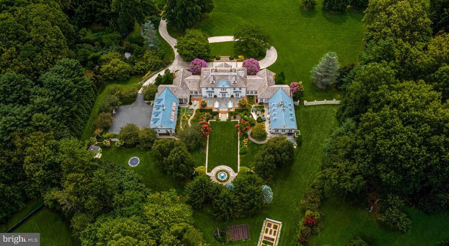 Gracefully sprawling across 4.56 manicured acres in Potomac’s coveted Golden Horseshoe, 9010 Congressional Parkway is one of the region’s premier estates. The residence embodies East Coast timelessness, blending the grandeur of expansive country manors with the tranquility of coastal retreats—all crafted to the highest finish level in the luxury space.  Originally designed by the esteemed architectural firm Versaci Neumann and painstakingly transformed by its current owners, the home underwent an exquisite restoration that introduced unique, imported finishes and bespoke elements from around the world, elevating its stature to new heights of luxury.

As you arrive, automatic gates part to reveal a meandering, newly laid driveway leading to a central motor court lined with pavers. The estate’s architectural significance is immediately apparent, with symmetry-driven design complemented by lush, tailored plantings. Federalist-style double doors open to a grand rotunda, introducing a gracious floor plan spanning 15,451 square feet of sophisticated living space.

Formal rooms radiate from the grand foyer. The living room extends 34 feet, anchored by a roaring fireplace and lighted, molded built-ins shimmering against lacquered walls and ceilings. A marble wet bar with smoked mirrors connects to the custom-paneled sitting room, which opens to gardens via French doors.

The informal areas carry a coastal flair, starting with the chef’s kitchen, where soaring beamed and shiplap cathedral ceilings frame the space and whimsical antique theater lights imported from Paris are a show-stopper above the oversized center island.  Redundant commercial-grade appliances are nestled within furniture-grade inset cabinetry and waterfall countertops. The adjacent family room features a mirrored ceiling design, masonry fireplace, and chair rail moldings that complement built-ins, creating an intimate yet expansive atmosphere.

The solarium and garden cutting room dazzles with inlaid marble floors, built-in planters, and intricate latticework, seamlessly connecting to the outdoors, storage areas, and mudroom. On the opposite end of the main level, the private primary retreat boasts soaring ceilings, a gas fireplace, and a sitting room with direct outdoor access. The marble-clad ensuite rivals world-class resorts and is paired with two dressing rooms, each with a center island. Directly connected to the suite is a spectacular game room with cathedral-beamed ceilings, a masonry fireplace and custom paneling, leading to a fitness center that opens to an outdoor terrace with a spa and shower.

The second floor features four spacious bedrooms and three baths surrounding the rotunda. A third-floor suite enhances versatility, while a separate apartment above the four-car garage offers additional accommodations.

The lower level centers on entertainment, with a large recreation room, wet bar, and private cinema professionally designed with tiered seating and high-end equipment for an unparalleled viewing experience.

Outside, the estate’s meticulously maintained grounds draw inspiration from grand European properties, blending hardscaping with exquisite landscaping. Features include a koi pond, trickling fountain, vegetable gardens, and four separate sheds, creating a serene, natural oasis.

Supported by industrial-grade systems rarely seen in a residential setting, the estate is a fortress of luxury. Conveniently close to Washington yet offering complete seclusion, 9010 Congressional Parkway stands as a globally distinguished estate, embodying impeccable craftsmanship and timeless elegance.