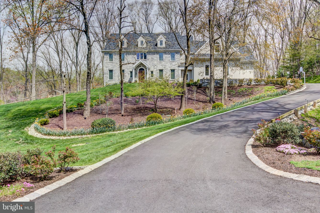 8 Cossart Manor Road, in the heart of Chadds Ford is situated on a stunning lot offering privacy and views in the desirable location just off the historic Route 52 corridor and just North of the DE border. This stunning custom-built Bancroft home is set on a large 2-acre lot in Pennsbury Twp with 5BR, 6.1 bath and spares no lack of high-end finishes throughout. Set back on a hill and adjacent to protected land, this stately home will leave a lasting impression. A long driveway approach will lead you to extensive hardscaping and landscaping on the way to the formal entrance. Head through the covered portico into the dramatic 2-story foyer with turned staircase, marble flooring and custom millwork. To the left is the formal living room with large picture windows. Continue through to the dining room with tray ceiling. Through French doors, enter the spacious eat-in kitchen with oversized center island, top of the line appliances including Wolf gas range & double ovens, Subzero refrigerator and Bosch dishwasher. The kitchen opens to the step-down family room with high vaulted ceiling and gas fireplace. To the right of the foyer is a private main floor suite. A sunroom with slate floor, full bathroom with a subway tile shower, powder room, laundry room and access to the attached 3-car garage complete the main floor. Head up either the main or back staircase to the second floor. Enter the luxurious primary suite with well-sized bedroom, sitting room/office and beautifully updated en-suite with claw-foot soaking tub, walk-in tiled shower and dual vanity. There is a bank of custom closets in addition to a large walk-in closet as well as second sitting room. This area could easily convert to a 5th bedroom on upper floor if needed. There are additionally 3 bedroom suites and a spacious walk-in coat closet that completes the second level. The walk-out lower level provides a 5th bedroom, full bath and a sitting area - perfect for entertaining - with family room and two-burner kitchenette with new countertop, backsplash and sink. This will provide great options for in-law suite or overflow guests. Outdoor spaces include and inviting stone patio with outdoor kitchen which provides extra living space with sweeping wooded views of the professionally hardscaped & landscaped grounds. Additional amenities include a preplanned space for elevator, gas line run for a possible pizza oven for the outdoor kitchen, newer temperature controlled wine cellar, and Andersen replacement windows in bedrooms and front of home with Hunter Douglas window treatments on main floor windows. All this and more in the acclaimed Unionville Chadds Ford School District. Peaceful country lifestyle minutes away from shopping, recreation, schools, Brandywine Valley, Wilmington & Philadelphia.