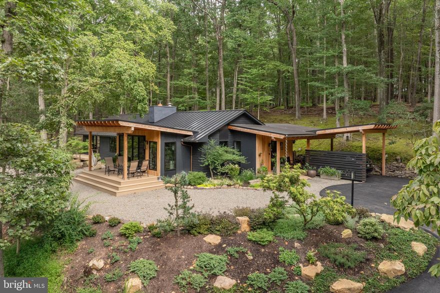 Nestled within the greenery of New Hope, an extraordinary retreat is tucked away- welcome to Moss Hill. This property is a fully revived Mid-Century Modern home, designed by Chris Pickell & Associates, and meticulously renovated in 2024, sparing no expense. Each component of the home was thoughtfully deliberated, merging classic architectural design with state-of-the-art systems, energy-conserving enhancements, and bespoke finishes. The house was stripped down to its bare studs and reconstructed with brand-new electrical systems, high-grade PEX plumbing with manifold, efficient HVAC systems, foam insulation, and superior Marvin Elevate windows and doors. Elegant laminated beams arch the ceilings, while expansive 8' x 12' sliding doors admit an abundance of light and a sense of the outdoors. Modern steel elements, Hardie board siding, a standing-seam metal roof, and Douglas Fir porch features contribute to the home's distinctive curb appeal. Within, the layout is characterized by smooth lines and open spaces. The kitchen, equipped with custom Plato cabinetry constructed from Shou Sugi Ban, a Wolf induction cooktop, a Wolf M Series oven, a Bosch refrigerator, a Fisher Paykel drawer dishwasher, and a bar area with charred wood accents, is the center of the home. A pair of Velux skylights wash the space in natural light, while a stunning wood-burning fireplace with a customized steel surround adds warmth and aesthetic appeal. Every room exudes luxury and thoughtful design. Mirage white oak engineered floors extend throughout the home. The bathrooms provide an experience akin to a luxury spa, with Grohe curb-less showers, heated floors, Robern anti-fog mirrors, towel warmers, and Japanese-style bidet toilets. The master bath is a haven of tranquility, while a unique stone Japanese soaking tub is a highlight of the guest bath. Custom-designed closets by Closet Works add to the home's appeal. In terms of technology and convenience, the home is equipped with a whole-house WiFi system, Honeywell smart thermostat, Bosch high-efficiency heat pump, Briggs & Stratton whole-house generator, reverse osmosis filtration, and a Bradford White heat pump water heater. Soundproofing and insulation were also upgraded beyond standard. The in-house and outdoor living experiences at Moss Hill are equally impressive. Several Azek composite decks extend from the living room and master suite, overlooking panoramic woodland views. A spacious bluestone patio with integrated drainage, newly landscaped grounds, and bold boulder features create an ideal environment for entertaining. The completely renovated gunite swimming pool (2025) boasts new systems, stone decking, and a revitalized pool house with a privacy screen and deck. Moss Hill's prime location is just minutes away from boutique shopping, exquisite dining, river activities, The Bucks County Playhouse, and is an easy 80-minute drive from NYC and an hour from Philadelphia. Combining the charm of mid-century modern architecture with modern efficiency, sustainability, and luxury, Moss Hill offers a unique living experience in an organically peaceful & private setting.