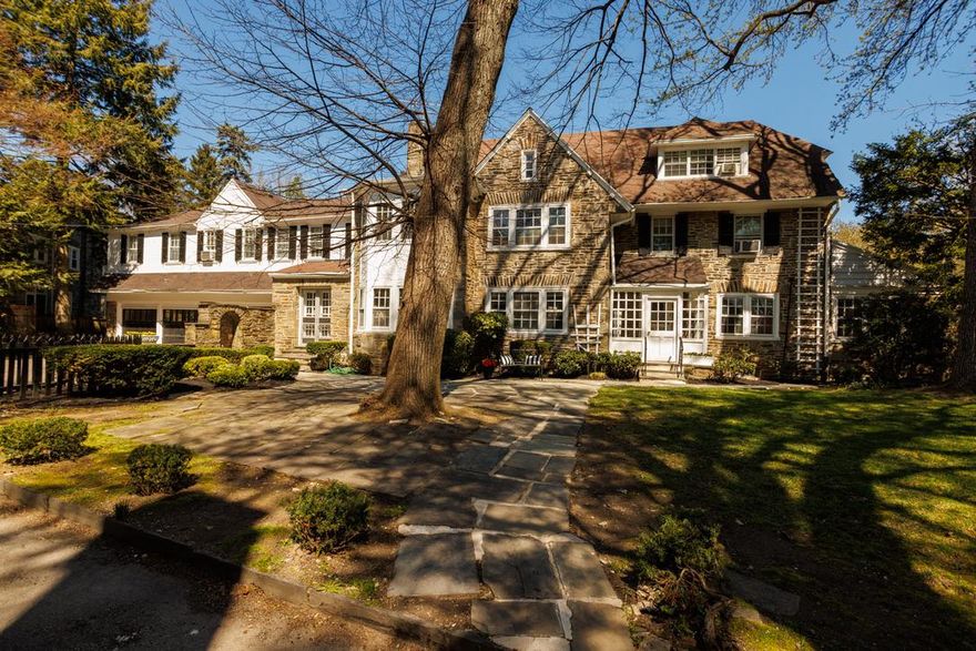 SMART BUY.  VALUE, SCALE, LOCATION! An exceptional and storied residence in the heart of West Mt. Airy, this grand 1925 stone Tudor-style home spans 5116 square feet and offers 7 bedrooms and 5.5 bathrooms, blending timeless architectural character with an opportunity for thoughtful updates.
Set back and gated from the street, this home offers privacy and a tranquil presence. From the moment you arrive, the home’s classic stone exterior, mature landscaping, and turn-around driveway set the tone. A stately red maple and blooming rhododendrons frame the property, while two large attached garages provide rare convenience. Inside, the home is rich with original details—arched openings, curved ceilings, hardwood floors throughout, three brick fireplaces, and beautifully crafted built-ins—hallmarks of its era and enduring quality. Enter through a side vestibule into a welcoming foyer with a central staircase. To the right, a generously scaled living room features a fireplace and bay windows flanked by built-ins, offering an ideal space for gathering. To the left, the formal dining room flows into a cedar-walled library with its own fireplace, French doors to the garden, and a tucked-away powder room.
The kitchen retains its original built-in cabinetry and connects to a pantry, back staircase, and direct access to the garage and surrounding stone pathways. The expansive unfinished basement offers abundant storage and houses the laundry.
Upstairs, the second level features a spacious primary suite, a front bedroom, and a hall bath, along with a sitting room that leads to a private rear wing with three additional bedrooms and two full baths. The third floor adds two more bedrooms, a full bath, and a storage room—perfect for flexible living arrangements.
Lovingly owned by a prominent physician and his family for over 65 years, this home is ready for its next chapter. While it would benefit from a refresh, the scale, craftsmanship, and layout provide an extraordinary foundation to enhance and personalize.
Set in one of Philadelphia’s most sought-after neighborhoods, West Mt. Airy is known for its tree-lined streets, historic homes, and strong sense of community. With easy access to Center City, Wissahickon Valley Park’s extensive trail system, and the shops and dining of Chestnut Hill, the location offers the perfect balance of nature, convenience, and charm.
A rare opportunity to steward a truly special home and bring new life to a classic estate.