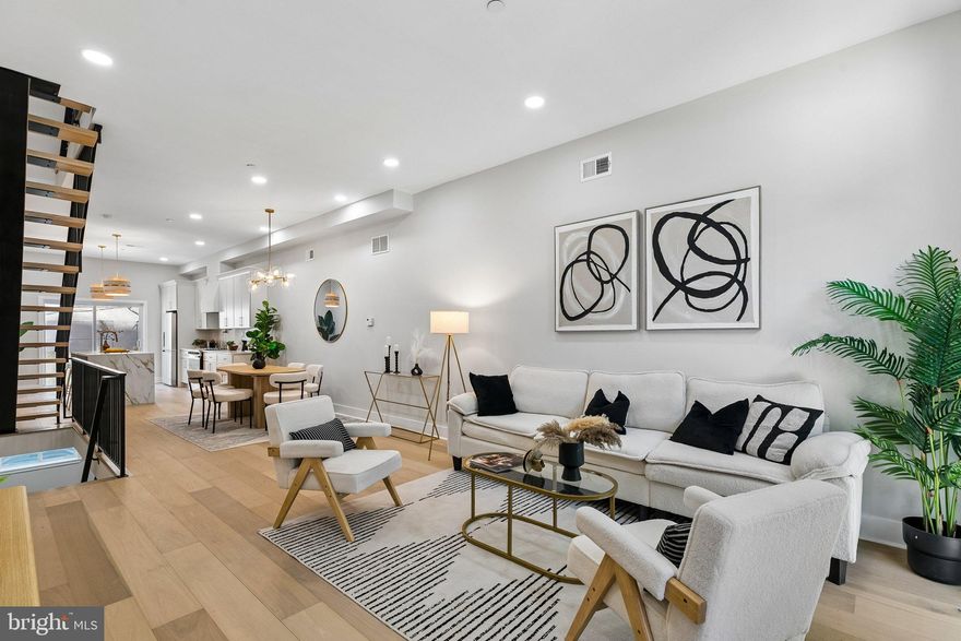 Welcome to 1439 S 8th Street — a stunning new construction home in the heart of Passyunk, one of Philadelphia's most sought-after and walkable neighborhoods. Perfectly situated just steps from the award-winning restaurants, boutique shops, and vibrant café scene of Passyunk Avenue, this four-bedroom, three full-bath residence delivers the ultimate in modern city living. From the moment you enter, you're greeted by wide plank white oak hardwood floors, soaring oversized windows that flood every level with natural light, and a dramatic floating staircase that serves as an architectural centerpiece. The open-concept main level is designed for both everyday living and effortless entertaining, anchored by a chef's kitchen featuring top-of-the-line appliances, custom cabinetry, and a stunning waterfall island — the perfect gathering place for family and friends. Upstairs, the generously sized bedrooms are outfitted with built-in closet shelving throughout, while the spa-inspired primary bath stuns with a freestanding soaking tub and designer tile work. The third floor offers incredible flexibility, complete with a wet bar and direct access to the expansive private roof deck — where unobstructed, panoramic views of the Philadelphia skyline await. Whether you're hosting at sunset or enjoying a quiet morning coffee above the city, this outdoor space is truly one of a kind. The deep lot also provides a sizeable backyard — a rare outdoor retreat in the heart of South Philly. This home is backed by a 1-year builder warranty and qualifies for Philadelphia's coveted 10-year tax abatement, offering exceptional long-term value from day one. Do not miss your opportunity to own a meticulously crafted, move-in-ready home that checks every box in one of the city's most beloved neighborhoods.