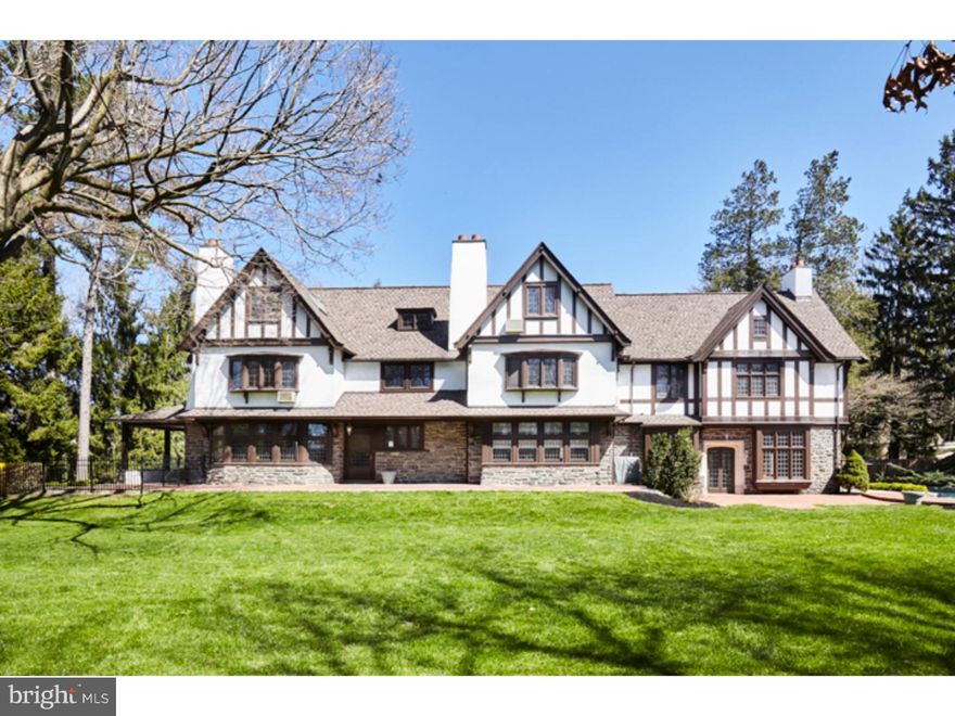 Best buy on the Main Line! Circa 1900 Tudor on 1.49 level acres. Features include: large graceful rooms with leaded glass windows; 7 fireplaces; detached 2 car garage & CARRIAGE HOUSE {(use as guest/ au pair/ in-law/tenant suite)-it has a large updated kitchen, living room, bedroom, bathroom, laundry and French doors to brick terrace}; professionally landscaped yard includes a brick and stone terrace and TREX deck with hot tub surrounding the free-form SALTWATER mountain pool with waterfall/waterslide and expansive fenced level lawns. Other features of the house include an impressive paneled entry hall with brick gas fireplace; large dining room with French doors, china cabinet and gas fireplace; impressive paneled GREAT ROOM (31 x 19) with built-in benches, 11' plaster molded ceiling and an enormous carved stone fireplace; a library with two sets of French doors to a covered porch, built-in bookcases, beautiful bow window and brick gas fireplace; enormous 2009 eat-in gourmet KITCHEN with two ovens, warming drawer, ice maker, pot-filler spigot, Thermador five burner gas cooktop, pull-out refrigerator and dishwasher drawers, farmhouse style kitchen sink plus 2 bar sinks, flat screen 50" TV, cabinets and granite counter space galore,  radiant heated tile floor and French door to deck. The grand open staircase leads to a transverse arched hallway. To the right is the master bedroom suite consisting of a bedroom, bathroom (with double sink, radiant heated floor, steam shower, heated towel bar) and sitting room with gas fireplace and a room-size walk-in closet. Three large bedrooms, two hall baths and a laundry room complete the second floor.  The third floor, consisting of three more rooms with hardwood floors, a kitchenette and bath, plus a true attic can be used as additional bedroom/living space or strictly attic. Partially finished basement consists of two playrooms and several others rooms for storage and mechanicals. Graceful semi-circular Belgium block-lined driveway leads to a very large parking area and the garage which adjoins the above-described renovated CARRIAGE HOUSE. Two storage sheds included. Extensive exterior lighting as well as interior high hat lighting within. First two floors are 6500 SF. 3rd floor adds about 2000 sf more. New central air, steam-fired gas heat, public water and sewer, newer roof, and a generator which was added two years ago all add up to a truly special family home. Like I said, best buy on the Main Line!