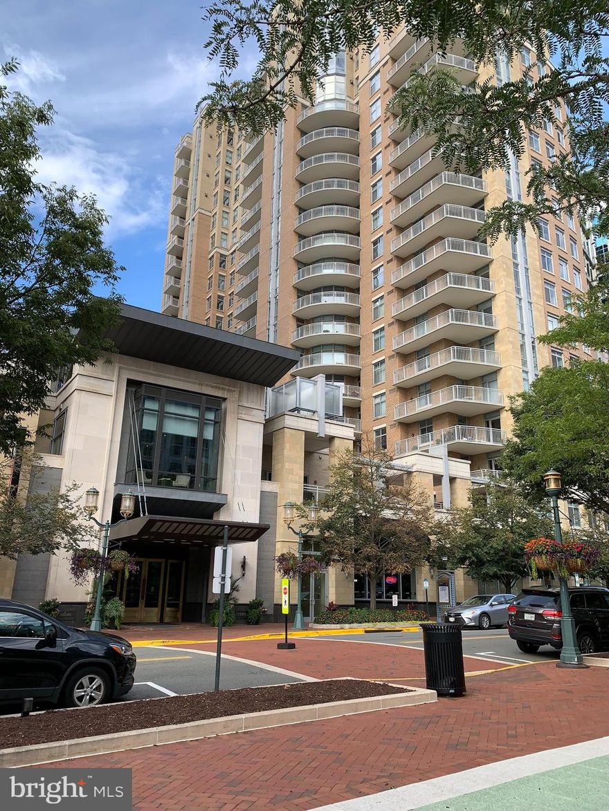 Exquisite 3 BR; 3 BA (2,283 sq .ft )  3 GARAGE PARKING SPACES;  BENTLEY model with high ceilings and TWO balconies offering stunning views of Tysons, Reston and the countryside beyond! This home exudes luxury while offering convenience with 24-hour concierge service and walking distance to Reston Town Center Metro.   Upon entering the home you’ll pass through an elegantly appointed foyer to access the LIVING ROOM with walls of glass and a floor-to-ceiling stone surround gas fireplace.  To your right you'll find an inviting KITCHEN boasting quartz backsplashes and waterfall island with a pop-up outlet, Wolf 6-burner gas Range & Double Wall Ovens with Steam Oven & Microwave, Viking Refrigerator, and Bosch Dishwasher.  The kitchen opens to a generous BREAKFAST ROOM with balcony and FAMILY ROOM with flat screen television, surround sound and a wall of cabinets housing a Whynter 164 bottle wine cooler.  On the opposite side of the living room, you'll take a hallway to a 2nd BEDROOM with a door opening to the balcony and across the hall is a FULL BATHROOM.  At the end of the hallway, you'll find the luxurious PRIMARY SUITE with separate SITTING ROOM, walls of glass and built-in closets leading to the en-suite bathroom which includes a vanity with double sinks, a make-up Vanity and shower.  The PRIMARY SUITE windows are complete with electronic shades. Off the foyer you'll find the 3rd BEDROOM, 3rd FULL BATH and laundry room. The bedrooms are carpeted; the main living areas have beautiful hardwood floors. Separate laundry/storage rm with washer & dryer!  SOME FURNISHINGS MAY STAY.  THREE ASSIGNED PARKING SPACES  (one with an electric car charger that tenant may use at their expense).  Utilities included in rent are gas, water & trash removal.   AMENITIES ABOUND, including 24 hour CONCIERGE service, an outdoor POOL and spa, 2 CONFERENCE rooms, FITNESS CENTER/FULLY EQUIPPED GYM, Entertainment kitchen, OUTDOOR GRILLS & Patio Tables,  MEDIA ROOM with Theater Seating & two GUEST SUITES for visitors. Steps to RESTON TOWN CENTER and all it has to offer!! Walk to dining of your choice including Bar Taco, Ruth Chris & Morton’s Steak Houses, FOGO de Chao, Barcelona, and Passion Fish! Whole Foods, Trader Joes, CVS and an abundance of shops within blocks!   Half mile (approx.) to RESTON TOWN CENTER METRO STATION. RESTON HOSPITAL is minutes away.  Easy access to Dulles Expressway and to DULLES Airport only 2 mi away.