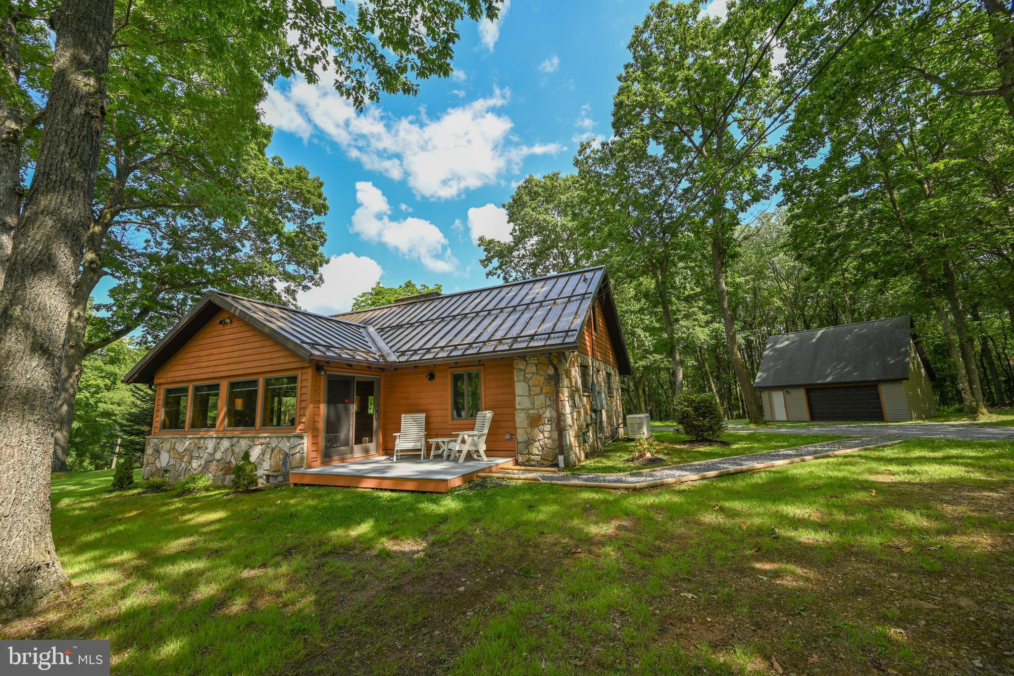 Just pack your bags and bring the family! This amazingly charming home has been perfectly remodeled. The open living/dining/kitchen has cathedral log beamed ceilings, beautiful hardwood floors, and surrounded by large windows to let the outside in. The most amazing stone fireplace sets off the room! The primary bedroom steps out to a covered hot tub. The has most wonderful attached bath with a large tiled shower. Main level has a 2nd bedroom and a charming second bath. Second floor spacious loft tucked away with cathedral ceiling and hardwood floors. There are two garages on the property. One is a 2 car garage with a spacious, finished room above. The garage that is closest to the home is almost finished inside and just like the home! Beamed ceilings and wood walls. This could be a fantastic game room, she shed, or man cave! This quintessential storybook cabin sits on 2 beautifully wooded lots. Enjoy evening smores and storytelling at the firepit, or relax in the covered hot tub area. Sky Valley has 3000' of common lakefront. 3 swimming platforms, sandy area, roped off swimming, and covered picnic areas, tot lot and basketball! It is like a private State Park for just for Sky Valley! Waiting list for boat slip but you can launch your boat right in the neighborhood until your slip opens up. Make this your perfect mountain lake retreat today!