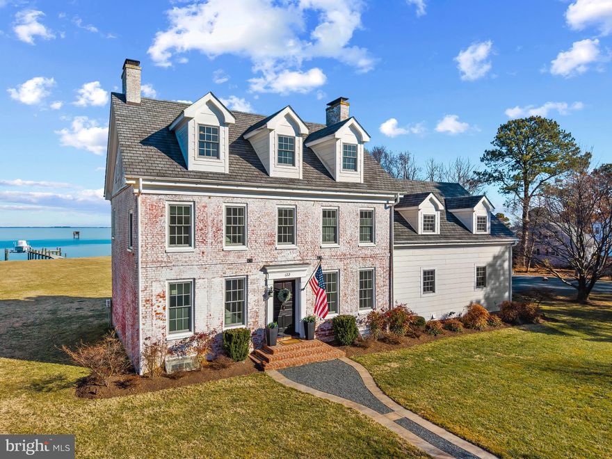 Originally built in 1778 and fully reimagined by Blue Heron Contracting during a meticulous 2012–2013 restoration and expansion, this extraordinary waterfront home in Kent Island Estates offers something rarely found: authentic 18th-century character paired seamlessly with modern coastal luxury.

Set on 1.3 acres with 175 feet of shoreline, the home captures sweeping, unobstructed views of Eastern Bay from every room. Reclaimed pine floors, four original brick wood-burning fireplaces, and pocket doors preserve its historic soul, while thoughtful expansion and design elevate it for today’s lifestyle.

The waterside chef’s kitchen flows effortlessly into the family room, creating an inviting gathering space where walls of glass frame panoramic water views. Whether hosting sunset dinners or enjoying a quiet morning coffee, the Bay is always center stage.

Upstairs, five spacious bedrooms include a generous primary suite retreat. Four fully renovated designer baths — including heated floors in the primary — blend timeless finishes with refined comfort. A stylish main-level powder room completes the interior.

Outside is where the Chesapeake lifestyle truly unfolds. A private 150-foot pier with 8,000-lb boat lift and sun deck invites spontaneous cruises and long summer days on the water. The bulkheaded shoreline with riprap provides both protection and natural beauty. A 30’ x 26’ waterside paver patio and fire pit create the perfect setting for sunset gatherings overlooking the Bay, all surrounded by expansive lawns and mature trees that offer privacy and serenity.

Additional features include a 26’ x 44’ detached garage with EV charging, workshop and boat storage, partially finished conditioned basement, dual geothermal heat pumps (5 zones), a 20KW generator, and an owned 1,000-gallon buried propane tank.

This is more than a historic home. It is a true Chesapeake Bay legacy property — where boating, entertaining, and panoramic views become part of everyday life.

Experience waterfront living the way it was meant to be.