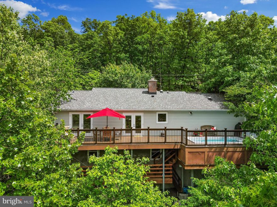 Absolutely immaculate 2 bedroom, 2 bath cottage perched on 3.65 private acres high on the mountain with beautiful views of the Shenandoah Valley and an Endless Pool high in the treetops! This eco-friendly home has been custom crafted with meticulous care: highly insulated house siding and walls, reclaimed American Elm floors, bespoke wood cabinetry and trim throughout, local soapstone details, handmade tile, specialized storage in all the closets and so many details it is hard to see it in one visit. Approaching the home, note the tranquil tones of the fountain, and the curated collection of native woodland plants in the professionally designed gardens. Likewise, note that the dry-stone stream beds hide a sophisticated drainage system to protect the home. The inviting front porch is made of the tropical hardwood Garapa, for both longevity and resistance to weather. Likewise, the expansive back deck is made of Garapa wood, but more on that later. The entry is lit by multiple skylights and broad windows and welcomes you into the open floorplan with glimpses of views off the deck. The unique fireplace mantle is made of fine Australian hardwood and matches the millwork throughout the home. The raw silk curtains and custom Hunter Douglas blinds convey with the property. Notice the charging station and bespoke storage details in the hall closet, and the storage solutions in all the other closets. The second room has hand-made, built-in cabinetry providing a stylish work from home space, and room to lounge and relax.  In the kitchen, enjoy more solid wood hand-crafted cabinetry, soapstone countertops, a fireclay farmhouse sink, soft close drawers, and exceptional storage solutions. The range is a US made Blue Star professional-grade gas with 22,000 BTU burners and a pot-filling spigot above. The primary bedroom is full of light and French doors to the deck with his and hers closets and built-in shelving. The primary bath has a heated floor, hand-made tiles, a marble countertop, and the tub is extra deep for soaking. The second bath mirrors these details and has a bespoke cherry wood cabinet and marble top. To return to the deck, the heated Endless pool is half pool and half spa on the deck with some truly impressive professional engineering carrying the deck and anchoring it deep into the mountainside. Whether you want a workout, a party, or a soak, this pool has the action to make it happen. Enjoy the stunning views while relaxing in the pool which can be used all year round. There is also ample space for dining, gatherings or entertaining. The deck railings are beautiful Brazilian Cherry to carry the ambiance of understated luxury to every detail. Your privacy and exceptional views are ensured as the house is situated on a large parcel, and there is also the potential to expand or build. Additional usable insulated space is available in the garage, which boasts its own expanse of cleverly built custom cabinetry and laundry room. There is a full unused, unfinished level with another deck below the main level, so let your imagination run wild. The garage and the lower level are fully wired, climate controlled, and lit for working out or indulging your favorite hobbies. If gardening is your passion, enjoy the stunning mature gardens and a handy shed for storage. Never worry about power loss as the house has a top-of-the-line propane fueled Siemens generator which will keep you comfortable during emergencies as well as heating the pool.