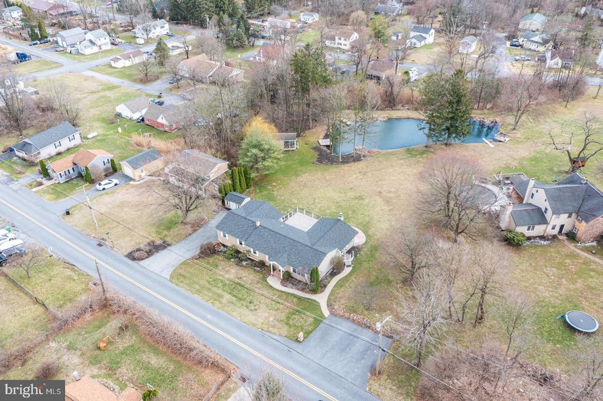 Welcome to this spacious and versatile ranch home set on a half-acre lot, offering the ease of one-floor living with room to grow. This custom ranch home has quality materials throughout and features five bedrooms and three full baths.  Step inside to a stunning great room with vaulted ceilings and a cozy wood-burning fireplace, perfect for gathering or relaxing. The well-appointed kitchen is designed with both style and function in mind, offering granite countertops, a large center island, breakfast bar, tile backsplash, farmhouse sink, pantry, and open shelving. A dining area adds additional space for your holiday meals. The main-level primary suite is filled with natural light from numerous windows and includes private access to the two-tier composite deck that overlooks the pond and is ideal for enjoying quiet mornings or evening unwinding. The primary bath features a large soaking tub and Corian countertop vanity. Three additional bedrooms and a full bath complete the main level, along with a spacious laundry room equipped with ample cabinetry. The deck is easily accessible from the great room, primary bedroom, and laundry room, creating a seamless indoor-outdoor flow. The walkout daylight lower level expands your living space even further, featuring a large rec room, a sitting area with a built-in reading nook. An additional room offers the perfect space for a home office or playroom, while the fifth bedroom and full bath provide ideal accommodations for guests or extended living arrangements. With its own entrance and separate parking area, the lower level offers excellent potential for multi-generational living or private guest quarters. Built with quality materials throughout and thoughtfully designed for comfort and flexibility, this home offers space, functionality, and endless possibilities.