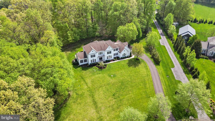 Introducing an exquisite and rarely available gem nestled within the picturesque confines of SOLEBURY Township's prestigious Symphony at Solebury community. This captivating residence, an expanded St. Regis model, boasts a staggering 5,376 square feet of opulent living space, bathed in privacy and meticulously crafted to redefine luxury living! Upon entry, guests are greeted by a grand foyer adorned with Canaletto ceramic flooring, accentuated by granite inserts, and crowned by a gracefully curved staircase, together setting a tone of elegance and sophistication. The main living areas have been artfully expanded, seamlessly merging spaciousness with functionality catering to endless entertainment possibilities. At the center of the home is the two-story family room, featuring a dramatic wall of windows that flood the space with natural light while the wooded views preserve your privacy. Adjacent to this inviting haven is a beautiful work-from-home office presenting hand-crafted cabinetry and serene views. A conservatory addition with windows galore welcomes the outdoors in, and offers a tranquil retreat ideal for movie nights, gaming sessions, or post-dinner gatherings. For the discriminating chef, the gourmet kitchen beckons with its expansive layout, including a breakfast room addition, and gas cooking! An oversized 10-foot island, and a plethora of amenities including a walk-in pantry, top-of-the-line built-in refrigerator/freezer, beverage refrigerator, a butler's pantry area with glass display cabinets, under-counter lighting, and a convenient workstation, are just a few of the advantages offered in this culinary space, and it’s a joy for those catered events! Formal dining is elevated to an art form in the phenomenal dining room outfitted with architectural wood details, providing the perfect backdrop for hosting holiday brunches or entertaining esteemed guests and colleagues! Retreat upstairs to the sumptuous owner's suite, where a coffered ceiling sets a tone of luxury. This private sanctuary boasts a sitting area with built-in bookcases and leads to a spa-like bath featuring a jetted oversized shower, soaking tub, and dual vanities. The pièce de résistance is the amazing owner's closet, meticulously appointed with custom built-ins to accommodate even the most discerning wardrobe. Custom plantation shutters throughout this sprawling suite allow for daylight and privacy! All upper-level secondary bedrooms feature en-suite baths and spacious closets, plus the windows display fabulous views no matter which room you choose! The lower level presents an opportunity limited only by your imagination, offering a full footprint of the home with extra height, rough-in plumbing for another full bath, and convenient walk-up access to the fabulous outdoor oasis. Step outside to discover a sprawling 1,800 square foot paver patio complete with a custom-built Weber grill kitchen and fire pit, perfect for alfresco dining and entertaining amidst the trees and the tranquility of 2.5 acres of landscaped serenity. The irrigation system covers approximately one acre, including the lovely hibiscus garden! The residence provides 3-zone heating and cooling and is also protected by a Generac whole-house generator. A built-in speaker system is offered in most of the shared areas and outdoors! The pristine condition of this property is evident in the freshly painted front elevation and squeaky clean Hardi-plank artic white siding! Welcome home to a sanctuary of unparalleled elegance and comfort in the heart of Solebury Township just minutes from Peddler’s Village, the vibrant restaurants, shoppes and playhouse in downtown New Hope, NHS schools and convenient access to major arteries! This perfectly maintained property awaits you just in time for summer evenings sitting with friends around a crackling fire with your favorite tunes playing in the background watching the fabulous evening sunsets!