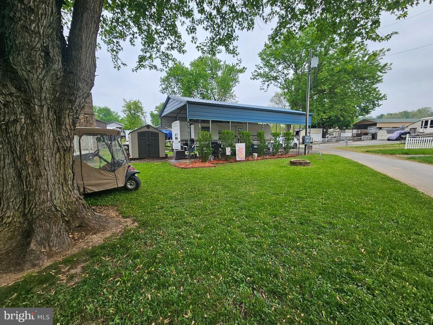 Block 2 Lot 6 Boo Boo is priced to sell and such a beautifully manicured lot. You can feel the love these owners have given it and they are now ready to transfer it to you. Situated on a flat ground and a corner lot is a spacious area to relax around the firepit, set up corn hole, take a nap under the tree, or whatever your heart desires. Maybe even extra parking although there currently is a paved driveway. Housed under a large metal pavilion sits a 2008 32 FT Forest River Wildwood Camper. The camper has 2 bedrooms, the primary on one end with a queen bed with a mattress topper for added comfort. This room also has a small Tv that has a Dvd player attached to it for movie night in bed! On the opposite end of the camper is a pretty cool bunk room. It has 2-fold down single beds that fold up when not in use, a top bunk bed and a couch that folds down for a total of 4 more sleeping spots back there. Sounds like the perfect sleepover room to me! This room also has extra storage space as well as it's own entry door. The camper has the traditional fold down table and couch for extra sleeping if needed. The sofa has an extra pad on top for added comfort. Everything you see conveys even 2 Gas Golf carts! YES 2 Golf carts! This is a steal folks! The shed has power ran to it with 2 small refrigerators for extra food keeping space. All the tolls stay. This lot is Turn Key! Yep, that sweet Pitboss and propane table are yours too!  Riverbend is 400 Acres of SEASONAL recreational campground full of amenities located on the Potomac River in Falling Waters, Wv. OPEN APRIL 1 - NOVEMBER 1 - This is a fun & entertaining community, yet relaxing. Approx. 10 miles of Deep water on the Potomac River access for boating, fishing & swimming. Yearly membership ($1,987) plus a $200 initiation fee for new owners, includes water, sewer, electric, trash and the park amenities such as 3 pools, putt putt course, Horseshoe club, Boat club, Poker runs, Trick or Treat, Christmas in July, live bands, basketball court, tennis court, fireworks, car show, Church, restaurant, bar, convenience store (Great food), playground, volleyball, ball field and much much more. Join Riverbend Boat Club. Bring your golf carts, water toys and come enjoy life!