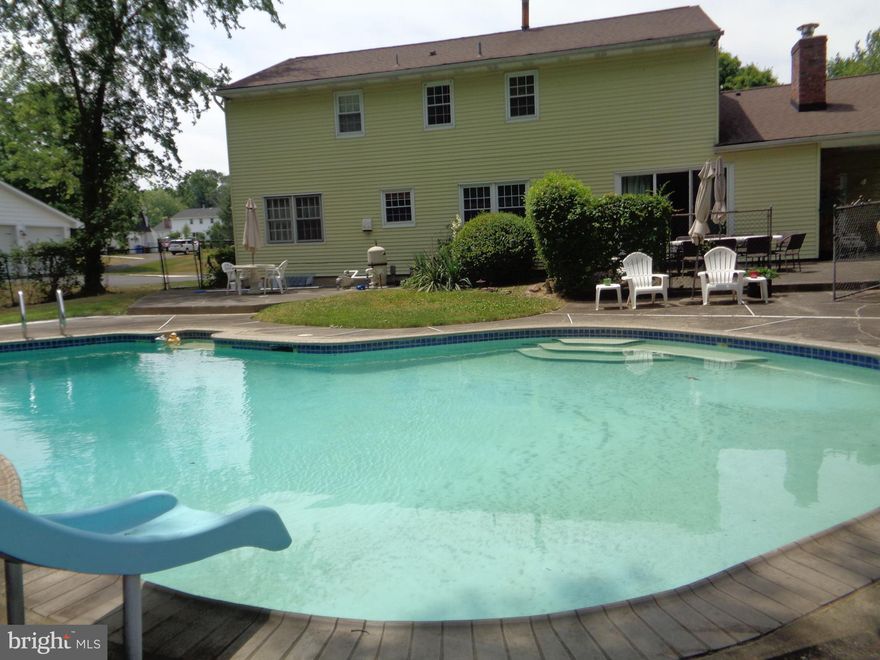 Have the best summer ever in this picture-perfect pool with sliding and diving board in Yardley and tons of room for all your family and friends in this 4,000+ sqft colonial-style home! 3 finished levels, 5 Bedrooms with hardwood floors, 3 totally renovated full Bathrooms, a massive Bonus Space ideal for an In-Law or Au-Pair Suite, and all on a premium lot that backs to Township owned protected space. Right off Makefield Rd, just past the Pennsbury Middle School Campus in prestigious LMT, sits this stately community of established homes on oversized lots lined in sidewalks, streetlights and neighborly waves as you head home. This brick-fronted colonial with dual walkways from the sidewalk welcomes you with its covered front porch and double door entry. Head into the Foyer to enjoy the vintage tile floors and neutral paint scheme t/out. To the right, you’ll find a formal Living Rm with a triple window and gleaming real oak HWF. Next, you’ll find the formal Dining Rm with ample space for your dining set, HWF, decorative tile ceiling, and double windows with views to the rear grounds. From the Dining Rm into the Kitchen gives a 30’ long open view to the end of the Family Rm. The Kitchen has ample wood cabinetry, window over the double stainless sink, vintage Spanish-style tile floors, pantry closet, recessed lighting and a newer stainless-steel appliance set including an upgraded 5 burner gas range, built-in dishwasher and side-by-side frig with water/icemaker. The Breakfast Rm has double windows and a room-divider with display shelving under an extended countertop to accommodate stool seating in the Family Rm. It also presents new carpet, built-in shelving along a floor-to-ceiling brick gas FP with wood mantle and newer chimney, a side door to a charming covered patio and sliding glass doors to a rear patio. Now that the “standard portion” of the Main Level is done, back off the Foyer is the In-Law/Au-Pair Suite area to review. Bright BR #5 has HWF and sits opposite a newer sparkling full Bath. A walk-in shower is lined in white tile with a European-style glass door, modern white tile floors, white vanity with granite top and decorator style lighting and accents. Just beyond that, down 2-steps, with beige carpet and relaxing paint is a massive flex space complete with Kitchenette and huge storage closet. There is also exterior access to this space without any steps needed- via the charming, covered patio on the rear side of the home. Head up the hardwood steps to the Primary BR Suite with newer carpet over HWF, ceiling fan, double closet + walk-in closet, dressing area and a beautifully renovated Bath. A walk-in shower is covered in neutral tile with a glass door, matching tile floors, white vanity with granite counter, crown molding & window. The 3 secondary BRs all boast original oak HWF & ample closets. The stunning Hall Bath is covered in white and gray marble tile, has a lovely gray/blue modern double sink/vanity topped in granite, window, linen closet and accent lighting atop beveled-edge adjustable mirrors. The professionally water-proofed finished Basement gives you an extra 700 sqft of open living space with white painted walls, recessed lighting and 3 windows. Storage Rm houses the HVAC, sump pit/pump, and additional crawl space storage. Tons of patio spaces offer multiple entertaining areas out back. Strategically planned fencing is placed enclosing a 10’ deep, colossal concrete pool sure to provide years of fun memories with its diving and sliding boards. Installed by Sylvan and professionally open/closed/maintained annually since installation. Beyond the rear fence is 5+ acres of LMT-owned land. Other notables: vinyl double hung replaced windows, chimney replaced, roof replaced in 2017, Carrier gas heater and Central Air 2016, HWH 2017. Desirable Edgewood Elementary & walk to Boehm Middle School. It’s time for a new generation to take over this property and LOVE LIFE HERE!