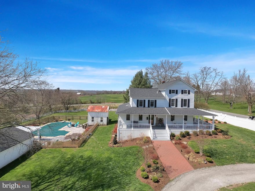 Classic farmhouse with modern style. This beautiful updated home is situated on a fenced 2 acre property with views of neighboring farmland. From the moment you step onto the wraparound porch, you will feel right at home. Floor plan was expanded and current owners have done loads of updates.  Kitchen is open and inviting with granite countertops, custom cabinetry and professional grade stainless appliances. Main level family room has adjoining full bath ( potential as a main level bedroom). Next level has beautiful, light filled primary bedroom, 2 additional bedrooms (both currently used for home offices) , updated primary bathroom plus a combination laundry room / powder room. There's one more level with 2 additional bedrooms. Basement is dry with concrete floor. Bonus room at Southwest corner has heat, water,electricity and lots of windows. Would make a great room for a green house! If you haven't fallen in love yet, there's more to see outside. The living space is expanded outdoors with plenty of places to lounge by the pool or relax under the pergola. There's a huge outbuilding that doubles as an indoor party area by the pool and still leaves plenty of space to function as a workshop. There's also a rustic "she"-shed / pool house and 2 rustic storage barns which are great for equipment storage. And if you like fresh eggs, there's already a chicken coop for you to start your own brood of hens! This is a must see property. One Year AHS Home Warranty included for added peace of mind. Virtual 3D walking tour available.