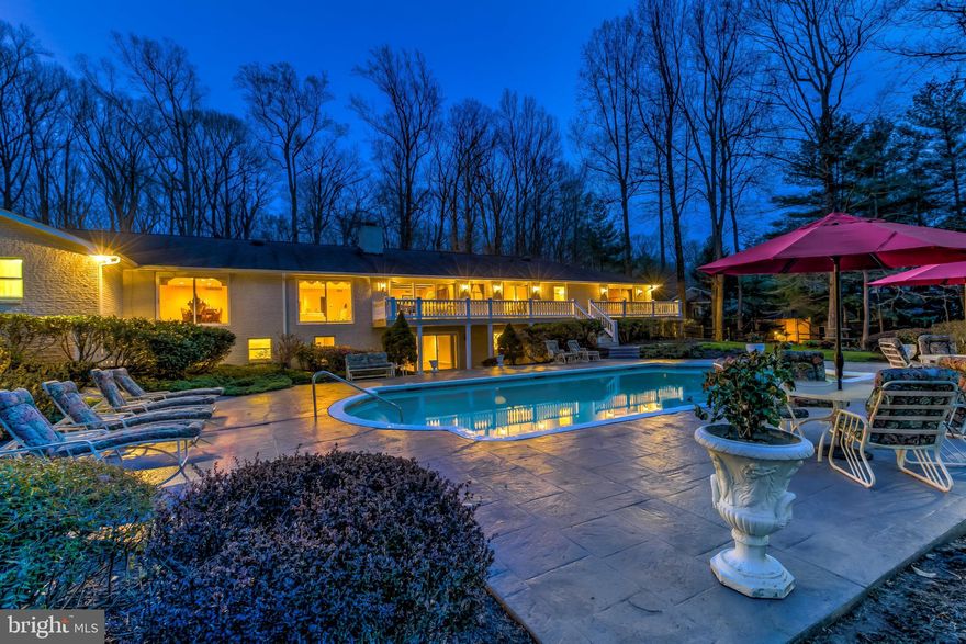 Perfectly positioned in the heart of the Caves Valley, this sprawling estate is nestled inside a gorgeous mature tree canopy that provides optimum privacy to its expansive grounds.  After passing through  an ornate gated portico, your first step into the Grand Foyer immediately conveys the most significant architectural impression of this home:  the ability to transfer the Outdoors experience "IN"!  The rear facade of glass communicates the lush beauty of the mature tree canopy and manicured landscape into every single living area of this home!  The generous floor plan design reveals graciously-proportioned living spaces throughout, including a capacious eat-in Kitchen with dramatic beamed Cathedral ceiling; spacious formal Living and Dining Rooms offer large windows overlooking the picturesque pool/patio/rear yard and allow abundant natural light inside. Main Level Bedrooms are conveniently located in their own wing on the Main Level; the Owners' Suite features TWO (2) Primary Baths including 2 walk-in closets and a separate Sitting Room/Office. The fully finished Lower Level has been recently refreshed and now presents simply fantastic Recreation or Entertaining space that walks out onto the pool patio and is replete with fireplace, full Kitchenette & Bar plus a separate wing for Pool Use (Full Bath, Changing Rooms + Boudoir).  Take advantage of the striking grounds this Spring/Summer and give yourself the Caves Valley Retreat you've been waiting for:  The pool, The patio, and the privacy!