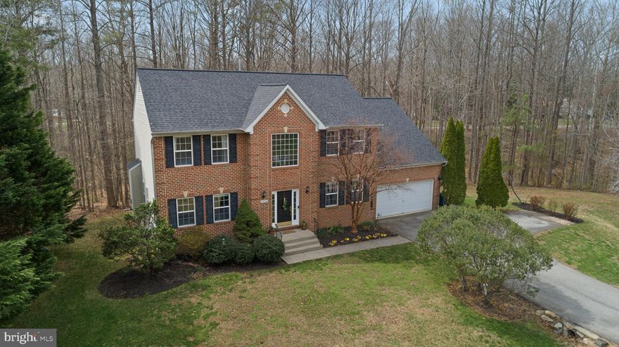Check out this beautiful brick home in Huntingtown offering a refined balance of comfort, space, and thoughtful design throughout, featuring 5 bedrooms (with the potential for a 6th) and 3 full and one half bathrooms.

An elegant sitting room welcomes you inside and leads seamlessly into a light-filled living room anchored by a fireplace and framed by large windows with classic white shutters. Rich wood flooring carries throughout the main level, adding warmth and continuity.

The kitchen is both timeless and functional, featuring granite countertops, stainless steel appliances, and substantial cabinetry. A double sink overlooks the private backyard, while pendant lighting, abundant windows, and sliding glass doors create a bright, inviting atmosphere. The layout flows naturally into the dining room, making it well-suited for both everyday living and entertaining.

Upstairs, a classic wood staircase leads to four generously sized bedrooms. The owner’s suite offers a true sense of retreat, with ample space, dual closets, and a well-appointed en suite bath featuring a marble double vanity, soaking tub, glass-enclosed shower, and linen storage. The additional bedrooms offer large closets and share a spacious full bath with dual sinks and ample counter space.

Outdoor spaces are equally impressive. The elevated back deck offers a peaceful setting overlooking beautifully maintained landscaping, with stairs leading to the yard below. A connecting walkway wraps to the front of the home, while a path extends to a cleared, tucked-away section of the property—ideal for a fire pit, seating area, or private retreat surrounded by nature.

The fully finished walkout basement adds exceptional versatility, featuring a desirable double-wide design with approximately half the number of steps of a typical basement entry, complete with a spacious recreation area, extensive storage, a well-equipped laundry room with utility sink, and a private bedroom with a full bath—perfect for guests or extended stays, and offering flexibility for a potential sixth bedroom. Sliding glass doors provide direct access to the backyard, enhancing the home’s indoor-outdoor flow.

This home delivers a rare combination of privacy, functionality, and understated elegance in a sought-after Huntingtown setting.