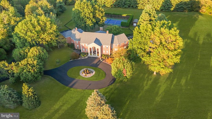 The Reimagined Twin Oaks: An Upper Makefield Sanctuary! Welcome to Twin Oaks, a commanding Georgian-style solid brick manor that seamlessly balances architectural grandeur with the comfort of a true family haven. Set at the end of an exclusive enclave of just nine estates spanning 90 acres, this 10-acre property has been significantly elevated through a comprehensive renovation. Arrival is marked by stately brick pillars with integrated lanterns, opening to a long, private tree-lined drive accented by classic lamp posts. The approach culminates in a circular driveway and a dramatic cantilevered front portico, centered by a breathtaking 20-foot custom fountain by Philadelphia Waterscapes. With bubbling spheres and cascading urns flowing into a self-replenishing pebble basin, this artisanal feature creates a serene, Zen-like introduction to the home.  Outdoor Living & Resort Amenities: The rear grounds have been transformed into a private resort designed for both grand entertaining and everyday relaxation. A massive swimming pool anchors the space, surrounded by an expansive stamped concrete patio and lush professional landscaping. A spectacular pavilion features a custom bar with seating and a stone fireplace for year-round enjoyment. A sprawling Trex deck offers a maintenance-free transition to the manicured grounds and the professionally resurfaced private tennis court. A dedicated dog fence encloses part of the yard with dual access to the four car side-entry garage and deck, providing both security and freedom. The Grand Foyer & Culinary Suites: Inside, a dramatic two-story foyer with boxed wall trim is flanked by twin butterfly staircases, drawing the eye toward the two-story great room beyond. The chef’s kitchen has been fully reimagined by luxury builders Worthington & Shagen and features a professional Viking range, Sub-Zero refrigeration with wine storage, and a built-in Miele coffee system. Designed for effortless hosting, a separate walk-in pantry room with custom cabinetry and shelving houses secondary appliances and entertaining essentials. This wing flows into a renovated mudroom and laundry suite, complete with a 38-inch stainless steel dog-grooming tub. Living Quarters & Wellness Wing: The layout offers a balance of scale and intimacy. The primary suite is a private sanctuary with a fully renovated bath featuring a custom steam shower, radiant heated floors, heated towel rack, TOTO toilet, and a couture-level dressing room created from a former bedroom. In addition to four other bedrooms, two expansive multi-room suites—each with 3 bedrooms—provide ideal accommodations for guests or multi-generational living. Eight additional en-suite baths have been expertly updated. The second level is completed by a spa room with a Zen ambiance, offering a sauna and two extra-deep luxury whirlpool tubs with inline heaters that can also function as cold plunges. The Club Level & Smart Integration: The walk-out lower level functions as a private social club with full Lutron smart-lighting integration. Highlights include an eight-person speakeasy bar, a state-of-the-art cinema with eight luxury recline leather seats, and an athletic wing featuring a basketball area with professional maple flooring and a glass-enclosed home gym. Two oversized storage rooms & a pool house section with a full bathroom complete this 2800sqft+ level. Turnkey Quality & Special Features: Mechanically superior, the home includes a new roof and updated high-efficiency systems. A fully integrated smart-home platform allows lighting, HVAC, theater features, pool systems, speakers, waterfalls, and lighting to be controlled via mobile device. Located within the Blue Ribbon–rated Council Rock North School District and minutes from Newtown, Princeton, and trains to NYC. With its scale, setting, and turnkey condition--at a fraction of the cost and time required to build new  --Twin Oaks is a legacy estate built for generations!