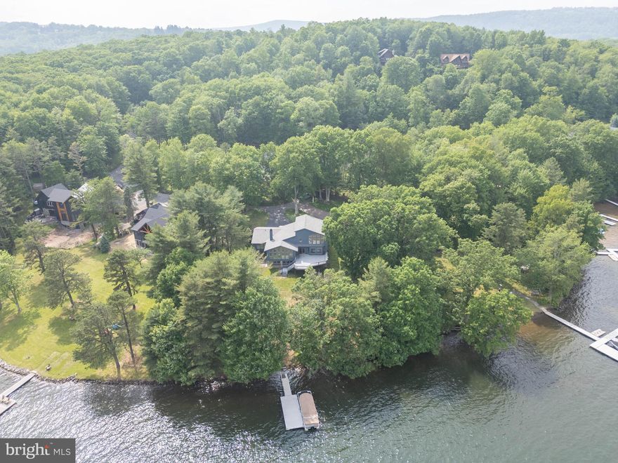 Panoramic lakefront living  greets you on the point of this remarkable 4 bedroom, 4 bathroom lakefront home with 231' of premium lakefront facing east, offering amazing sunrises looking down a long stretch of the lake toward Turkeyneck! 1 oversize attached garage spaces offer plenty of space for your vehicles on the street side and 2 attached garage spaces provide room for your lake toys on the lower level. An expansive deck provides plenty of room for outdoor entertaining, and multiple living spaces inside provide plenty of room for guests to enjoy their time at the lake. The Type A dock sits in deep water, great for swimming and enjoyment. The home sites on a private road and is the next to last home on the street. The location is just minutes from all of the area's most desirable restaurants, golf courses and Wisp Ski Resort! Buydown has been purchased and conveys.  Looking for an opportunity to own a premium waterfront home on one of the best settings at the lake? Call today to schedule a private tour!