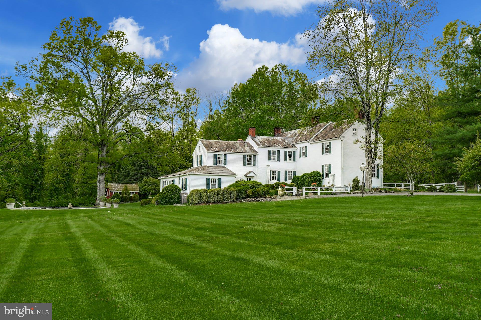 Historically, the most prestigious BUCKS COUNTY STONE manor homes were positioned on the high point of their acreage to overlook their fields and pastures, and with long driveways leading past bank barns and farm buildings. Such bucolic settings are rare now… but amongst them, Windwood, a gracious 1800’s GENTLEMAN'S FARM, stands out as an example of the very best. The approach is down a quarter mile LONG DRIVE, through mature woodland, to the center of 26 acres, nicely removed from a quiet country road. Windwood has a notable legacy, rich with tales of prominent visitors. Once known as the Guggenheim Estate, this gentleman’s farm embodies the quintessential details of Pennsylvania architecture, in a remarkable and private setting, above the DELAWARE RIVER from high atop Chestnut Ridge.
The 1800’s stone home has been enhanced with additions blending modern convenience with its history. Wide plank floors span both levels of the home. FIVE FIREPLACES, mullioned glass windows with deep windowsills, a central summer kitchen with BUTTERFLY STAIRCASE, exemplary woodwork and PERIOD HARDWARE attest to the 18th century character and timeless dignity.
The great room/kitchen addition boasts raised panel custom cabinets, a fireplace with raised panel cabinet surround and a wall of glass that opens to a bluestone terrace overlooking pool and meadow. Completing the first floor is an elegant living and dining room and charming central den, each with a fireplace. On the second floor, an open and airy master suite and large bath will soothe and pamper. The two additional bedrooms, one with fireplace, each with a bath, are perfect for guests and family. A whole house generator lets you relax and invite a crowd for summer weekends and every holiday.
Outside areas for intimate or formal gatherings abound. Patios with rock walls, a newly redone pool, and a hidden grotto amidst barn wall ruins, provide areas, at day’s end, for family and friends to gather. Weddings and other special occasions have always graced these outside venues, with memories that befit and embellish the history of the GUGGENHEIM'S SUMMER RESIDENCE. Adding to the property’s total ambience, the IN-GROUND POOL is surrounded by gardens, field and forest. The views from porch and patio provide an ever-changing panorama of verdant woodlands that provide seclusion in summer and long-distance winter views. Finally, in keeping with the role of a bespoke Bucks County Estate, there is a CARETAKER'S COTTAGE, garaging for three cars and a GUEST STUDIO above.
Windwood is a rare and elegant estate from a bygone era, in an exquisite and secluded Bucks County setting. Every aspect, both inside and out, is presented artfully and joyfully. This private paradise loses touch with the world just over the hills yet is still within easy driving distance to the magic of Bucks County dining, antiquing and recreation.