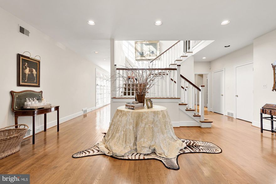 PRICE IMPROVEMENT!  Tucked away from the illustrious Iron Gate Road in the heart of highly sought-after Potomac Village is this handsome country estate. Sited on 2.18 wooded acres, at the end of a winding driveway, the approach makes an inviting yet dramatic first impression. Originally custom-built with interiors inspired by Katherine Hepburn’s Connecticut farmhouse, the home exudes timeless elegance, augmented by a sturdy brick facade and slate roof to withstand the test of time. Surrounded by wisteria vines, double doors reveal ethereal interiors sprawled across a substantial 9,463 square feet. Artistic in the way it flows in, natural light bathes the main staircase in a warm glow. Pocket doors off the foyer reveal a cozy octagonal study, with French doors leading out. The embassy-sized living room, measuring over 32-feet in length, is enveloped in natural light flooding in from skylights in the recessed cathedral ceiling. Two sets of French doors bring the outside in, while a roaring central fireplace, one of four in the home, retains a sensation of warmth within the vast space. Subtly elegant, the oval-shaped dining room features inlaid hardwood floors and overlooks the rear lawn. The country kitchen has been fully modernized, with a commercial grade range top, honed marble countertops, custom inset cabinetry, and a suite of SubZero-Wolf appliances. Touches such as the built-in bookshelf and adjacent breakfast area with fireplace enhance livability. A family room with three walls of windows and as well as a large screened porch overlooking the pool area complete the stunning main level. The primary bedroom’s raised ceilings and large fireplace contribute to the overall feeling of spaciousness, establishing an oasis. Twin walk-in closets and primary baths encompass all of the ubiquitous amenities, including a splendid clawfoot tub nestled beneath exposed wood beams and a walk-in glass and marble shower. Three additional large bedrooms, two full baths, and a cozy upstairs lounge are all thoughtfully designed. The lower level consists of an open space anchored by a billiards room with built-in seating and a recreation room with built-in shelving. A full wet bar, fitness room, lounge, full bath, and exceptional storage augments practicality and enables entertaining. The sprawling verdant lawns are surrounded by mature foliage for total privacy. Extensive hardscaping covers the acres of flat, usable space and includes large flagstone patios. A spectacular 50-foot lap pool with automatic cover sits against this natural backdrop for shaded swims on humid summer days. Timeless design, artfully restrained interiors, and a central Potomac location make 10004 Iron Gate Road the epitome of estate living.