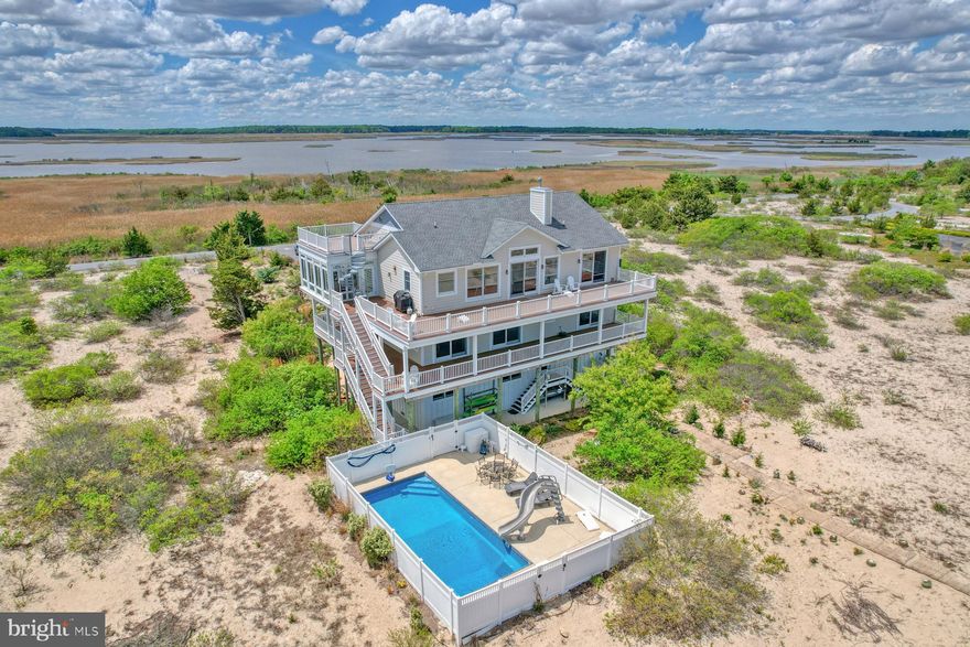 The Ultimate Bayfront Retreat! Welcome to Back Bay Cove — an exclusive, gated community on the northern edge of Broadkill Beach, where serene waterfront living meets breathtaking natural beauty. Nestled on 1.3 acres, this custom-built, five-bedroom luxury home with a pool and elevator, offers panoramic views of both the Delaware Bay and the protected Prime Hook National Wildlife Refuge. Custom built by Garrison Homes, a local award winning and highly reputable builder. Designed with entertaining and relaxation in mind, the 3rd floor showcases an open-concept layout, where expansive living spaces flow seamlessly into one another. The gourmet kitchen is a chef’s dream, featuring an oversized island, custom wood cabinetry, granite countertops, stainless steel appliances and a beverage fridge. A dining area and inviting great room with gas fireplace and soaring cathedral ceiling opens to a spacious deck, providing the ideal setting for soaking in spectacular sunrises and sunsets! A four-season sunroom with separate heat and air-conditioning was designed for ultimate relaxation. Head to the fourth-floor lookout deck via a spiral staircase for the perfect spot for stargazing or sunset cocktails. A custom designed office with built-in cabinetry provides the ideal workspace and library. The primary suite is a private sanctuary, offering stunning bay views, fireplace, deck access, a large custom walk-in closet, and a luxurious en-suite bath complete with an oversized glass steam tiled shower, double vanity, and a private water closet. The second floor is equally inviting, with four generous guest suites — each with private bathrooms and access to decks. The first floor offers a central living area with separate kitchen area, creating a perfect retreat as a multiple purpose entertainment and recreation area. The adjacent laundry room offers an expansive workshop with built-in shelving. On the ground level, the fun continues with direct access to an in-ground pool with privacy fencing, slide, patio area and an outdoor shower. The oversized two-car garage offers 10 foot high garage doors that can accommodate an RV and boasts custom cabinetry, and direct access to the encapsulated crawl space with new dehumidifier. Outdoor living is taken to the next level with beautifully connected decks, and a private walkway to the beach.  Additional features include: Solar panels, elevator servicing all three floors, 1st and 3rd floor laundry rooms, durable hardie lap siding, three zone HVAC system, insulated attic, abundant storage, irrigation system, security system, two tankless water heaters, collapsible wind screen on 3rd floor deck and invisible electric fence installed with separate loops in the front and back.  Whether you're seeking a year-round residence or a private beach getaway, this spectacular home in one of Delaware’s most unique waterfront communities is ready for you to enjoy. No crowds, just the company of friends, family, and nature’s beauty. Your dream bayfront lifestyle starts here! Contact the listing agent for details. Floor plans, elevation certificate and building specifications available upon request. Furnishings available per separate agreement.