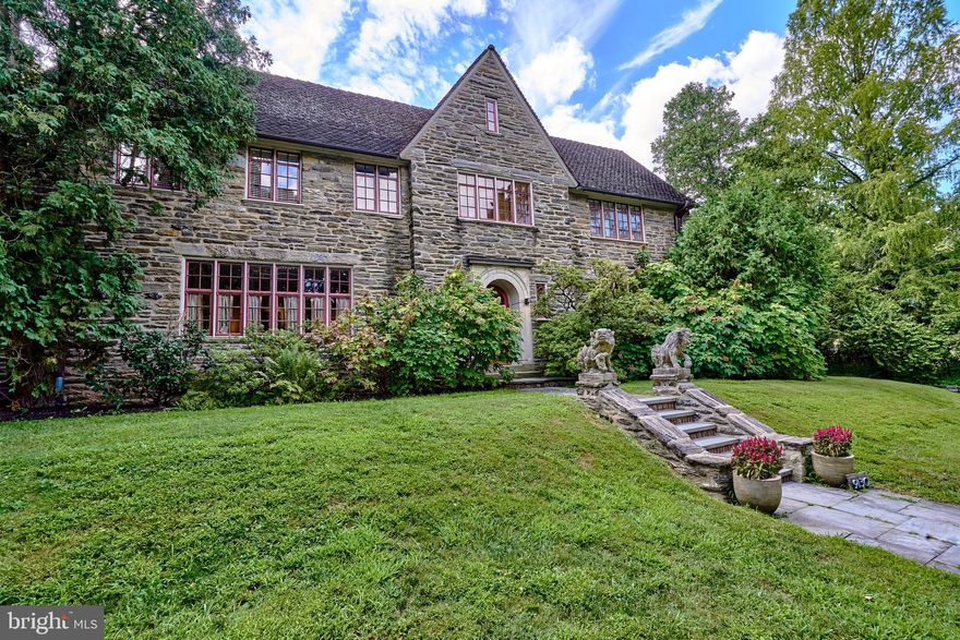 Rare opportunity to own this unique French  Center Hall stone home, perfect for entertaining in all four seasons. With extraordinary details both inside and out, this move-in ready home has been lovingly updated with a one-of-a-kind esthetic and attention to detail rarely seen in Chestnut Hill. Designed and built by the architect Judson Zane for his family residence, the home is situated to get wonderful morning and late afternoon light. The first-floor center hall entrance showcases a lovely sweeping Samuel Yellin iron staircase. A powder room and entrance to the lower patio are tucked under the stairs. The living room boasts an architect-designed contemporary fireplace and bookshelves with plenty of room for large gatherings, as well as an attached sunroom/media room with French doors to the rear terrace. On the opposite side of the center hall is a large dining room with built-in cabinets and original Asian Tea Foil Wallpaper that gently reflects the evening candlelight and wall sconces. The Bulthaup eat-in kitchen offers radiant heat, plenty of storage and is connected to a lovely family room with wood-burning contemporary stove and large screen TV. The family entrance off of the kitchen allows for easy load in of pets or groceries from the gated courtyard and garage. The second floor offers the large, southern-facing primary bedroom suite with balcony overlooking the rear terraces, full limestone bath with walk-in shower, and the original dressing room with cabinets that are hand painted with birds and flowers (This room could be the 5th bedroom if needed). Jack and Jill bedrooms on the opposite corner of the house share a large bath with walk-in shower. A studio/office with radiant heat has a new door with custom ironwork that leads to the rear terrace and pool, while upstairs is an additional guest room. Both rooms have access to a new soapstone bathroom with radiant heat, large soaking tub and steam shower. The large, stone walled backyard has multiple room-like sections, including: cutting garden for fresh flowers, Koi pond and stream, and heated saltwater pool with outdoor shower. Extraordinary stone terraced garden plantings, Japanese maple, pine trees and stone pathways give the backyard abundant privacy and a true feeling of wonder. A 2-car garage and full, walk-out basement complete this unique home. Set in a private yet convenient location in Chestnut Hill, this lovely home is a few blocks from 2 train stations for an easy commute into Center City, walkable to wonderful shops and dining, and offers easy access to the trails of Fairmount Park.