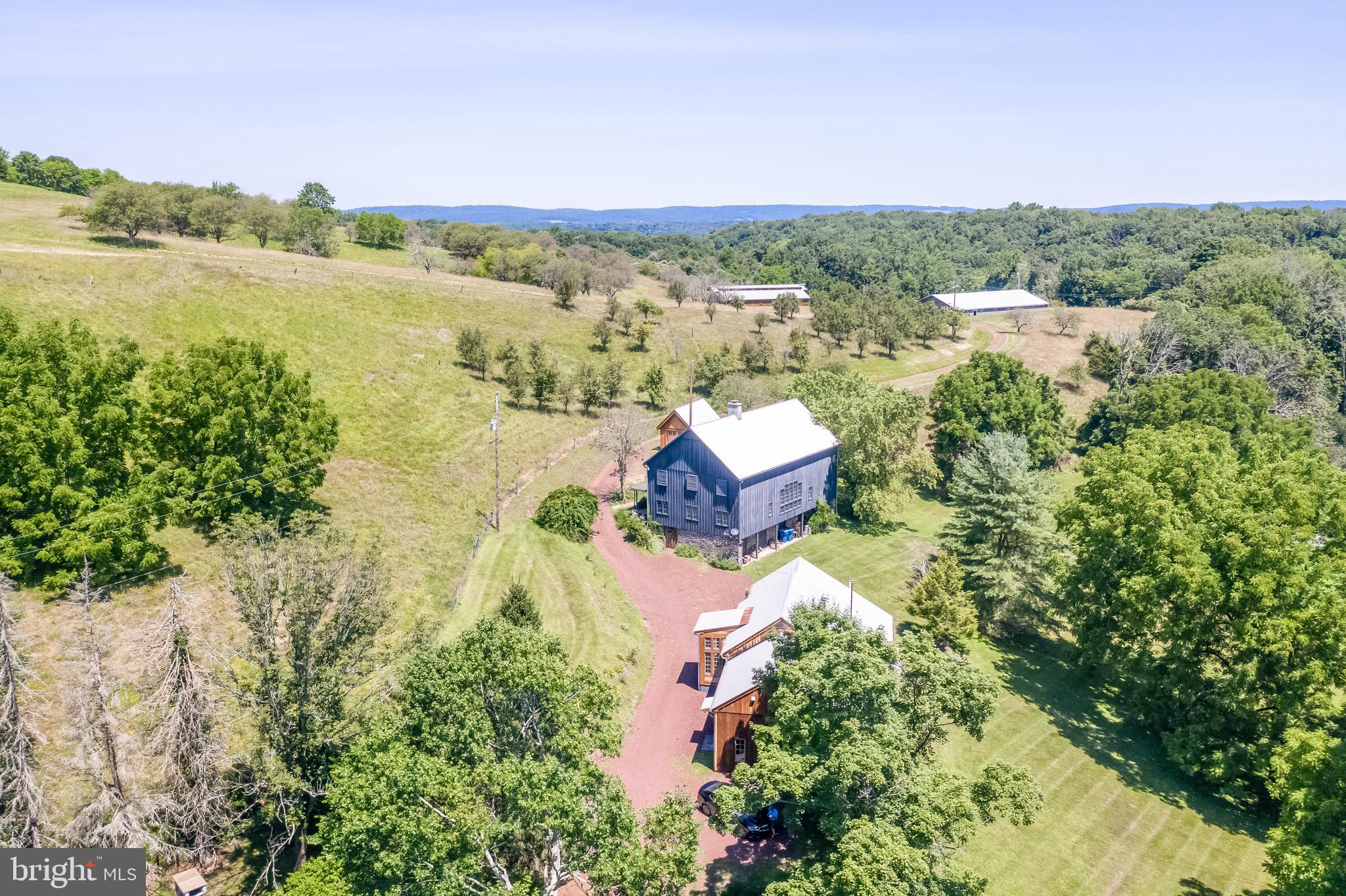 Absolutely beautiful eighty-one plus acres of rolling hills, panoramic views, four ponds and lush foliage just five minutes from the Delaware River - there is no other property quite like this one! The location is superb: down a winding country road midway between the Milford and Frenchtown Bridges, ninety minutes to either Manhattan or Philadelphia and a scenic twenty minutes to New Hope. The property has extraordinary long distance views and the serenity and stillness that comes from being surrounded by acres of unparalleled land at the very top of Tinicum Ridge. The entire property is permanently protected with Tinicum Conservancy to help preserve the rural character of the area and the conservation easements do permit the building of a spectacular new home. Currently the compound includes the original farmhouse, guest house, entertainment barn, huge working garage and hanger. Upon entering the gate you find the main house first. Originally built in the 1800's, the main part of the structure is post and beam with thoughtful additions made over the years. A wide rocking chair front porch leads to the farmhouse kitchen with distinctive custom cabinetry and top-line appliances. Typical in farmhouse kitchens the breakfast room and kitchen are one large room and flow to the great room. Wonderfully finished hardwood floors, handsome stone fireplace and a sweet library area with built in shelves are the features here. From the great room is the laundry room, mudroom and full bath with clawfoot soaking tub. On the second floor the master bath with cathedral ceiling and two additional bedrooms share the remodeled hall bath. On the third floor is the bonus room which would make a great media room or office. Central air keeps everything cool. The "Farm Store" or entertainment barn is the next stop on the winding driveway. Also originally built in the 1800's this post and beam structure was used as a farm store in the 1960's but has a new life as a spectacular entertaining barn. The fabulous 22x21 kitchen features subway tile, stainless triple prep sinks and storage and a massive 29x9 pantry room. Just off the kitchen is the large half bath. The hardwood floors in this building are fantastic and the ceiling and wall surfaces have been reskinned in wood. Three distinctive gathering areas (including a 30x30 great room, 51x12 dining room and 21x20 flexible use room), two wood stoves which have catalytic converters and 8 inch pipes that are extremely efficient, wine storage and display, walls of windows and a Trane HVAC system combine to create a stunning place to entertain guests. And where do your guests stay? The Guest Barn of course. This barn has been converted to living space with a two story great room with stone fireplace and Palladian windows overlooking the property. The calm and comfortable master bedroom has double closets and an ensuite bath with dual sinks and a tub/shower. A second bedroom can be found on the other side of the barn allowing your guests to each have their private space. A full modern kitchen and breakfast room, laundry area and second full bath complete this main floor. The lower level of the barn and the floored attic provide extensive storage. A detached one car garage is close by. Further up the lane is the "Apple Sorter" barn or the original barn where the apples from the farm were stored and sorted. The "Shop" was always the shop for the farm and is now the multi-car working garage. Significant work was done to refurbish this building and it is great for the serious car enthusiast or can suit a variety of purposes. The 66x45 "Hanger" is all the way at the top of the drive and has a fabulous panoramic view. Historically this was an airstrip and Erkes Airstrip can still be seen on maps. Conservancy information and documents available upon request. This is a once in a lifetime opportunity to purchase a history, natural beauty and a place to get away from it all.