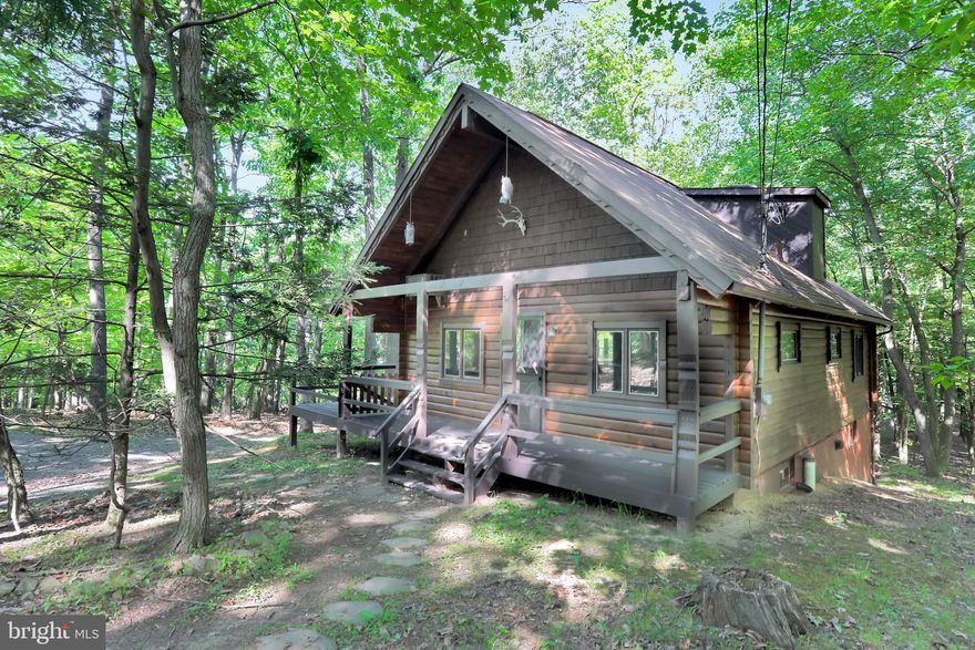 If you are looking for a true solid log cabin, come and take a look at one of the few that were built in The Woods Resort. And it's on a wooded corner lot. Suitable for full time living or that perfect weekend getaway, this property offers 2 bedrooms and 2 full baths. The main level has an open concept with living, dining and kitchen areas.  High wood ceilings in the living room with a remote control ceiling fan. Large kitchen with a double door built-in pantry, all of the appliances and a stone kitchen counter backsplash. A breakfast bar and dining area separate the kitchen and living areas.  Sliding patio doors lead out to a freshly stained deck for outdoor entertaining. You will also find a bedroom and full bath on this main level. The upper level has a bedroom with a full bath (shower) and a balcony loft area perfect for relaxing, reading your favorite books, or even working from home if you wish. And the full unfinished basement provides you with an opportunity to double your living area space. Class 'B' membership is available with this property.