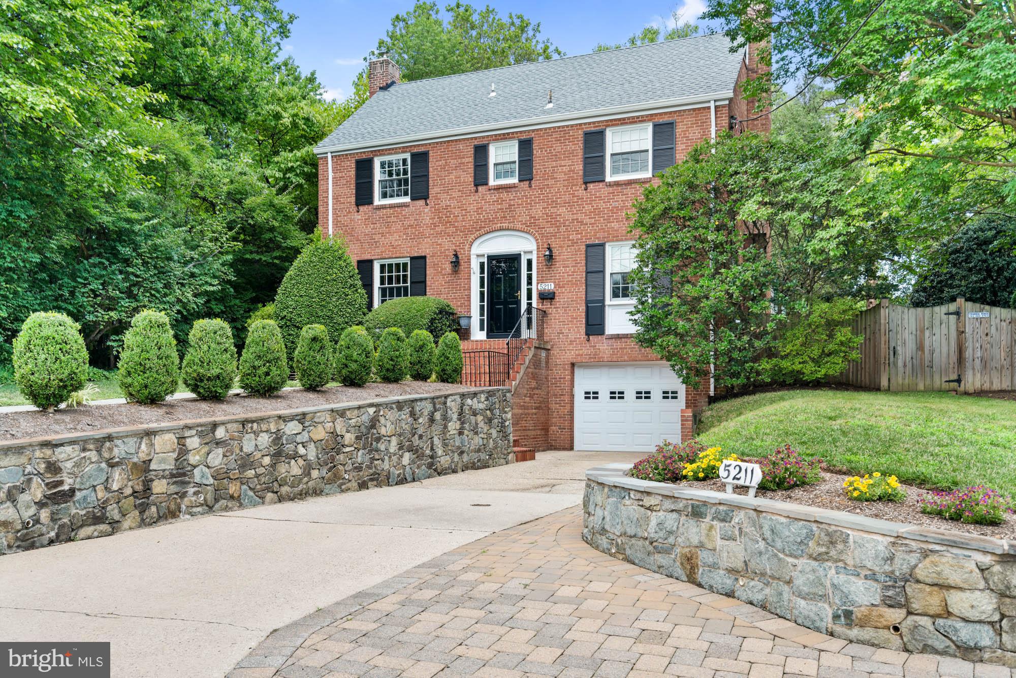 Classic charm with this updated 1953 brick Colonial, mere steps to Spring Valley (DC), Friendship Heights, the new Westbard Square, and the Capital Crescent Trail. Meticulously maintained, this three bedroom, three-and-one-half bath home enjoys sun-drenched spaces and excellent flow on three levels of living. Beautifully landscaped grounds and gardens frame the picturesque property and backyard. Quintessential details including hardwood floors, recessed lighting, cathedral and tray ceilings, a fireplace, and an attached garage. From Massachusetts Avenue, steps lead you to the front door. The first floor includes a center-hall foyer, a gracious living room, an elegant dining room, a sizable family room off of the kitchen with a bright and cheerful breakfast area, a sunroom, and a powder room. Kitchen is functional with opportunity to expand or update to today's style. Upstairs is highlighted by the spacious owner’s bedroom with multiple custom closets, built-ins, and en suite full bathroom. Two additional bedrooms and a full hall bath adorn the second floor, and a walk-up unfinished attic provides ample storage and a finishing opportunity. The basement with a separate entrance offers a recreation room; or use as a open fourth bedroom and full bathroom, creating possibilities for an in-law or au pair suite. 5211 Massachusetts Avenue benefits from neighborhood parks and trails and is convenient to Friendship Heights, Spring Valley, downtown Bethesda, the Capital Crescent Trail, and major transportation routes.
