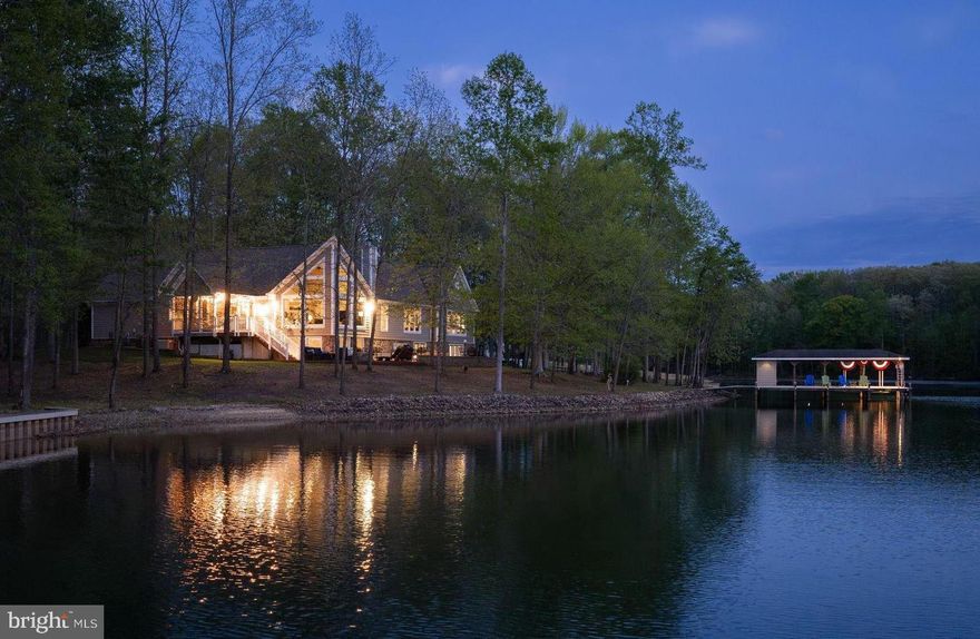 Tucked away on the private side of Lake Anna in Noah’s Landing Subdivision, this gorgeous custom-built waterfront home offers the kind of setting that’s hard to find—quiet, private, and right on the water. Set on 1 acre with 230 feet of shoreline and deep water off the boat dock, the property features riprap along the shoreline and a natural, wooded backdrop that enhances the privacy and views. High-speed Firefly fiber internet is available, bringing fast, reliable connectivity to this peaceful lake retreat. Inside, the home is filled with thoughtful upgrades and timeless finishes. The great room showcases vaulted ceilings, expansive floor-to-ceiling windows designed to maximize the lake views, and a wood-burning stone fireplace that anchors the space. Hunter Douglas remote-controlled blinds add both comfort and convenience. The spacious kitchen is built for gathering and everyday use alike, featuring stainless steel appliances, granite counters, a walk-in pantry, center island, soft close cabinets, and a breakfast bar with seating. There is also a stylish wet bar with silestone countertops. Engineered hardwood flooring runs throughout the home, complemented by 9-foot ceilings and a spacious, open layout that creates a bright and connected feel from room to room. The layout offers 4 bedrooms, including a main-level primary suite along with a dedicated home office with french doors and 3.5 bathrooms—giving the home flexibility for full-time living or extended lake stays. The lower level offers a welcoming family room, three bedrooms, and two full baths—including one with its own private ensuite for added comfort and privacy. Two of the bedrooms are finished with plantation blinds, adding a clean, coastal-inspired feel that enhances the relaxed lake lifestyle. Outside, the backyard opens up to a massive paver patio with multiple defined areas for seating, dining, and gathering around the fire pit. It’s a natural extension of the home—an easy place to spend the day from morning coffee to evenings under the stars. There is also a dedicated propane line for the grill making grilling out a breeze. From here, a gentle path leads down to the water and boathouse featuring an electric lift, storage room, and a large sun deck that sits right over the deep water. Additional upgrades include a whole-house generator, lake-fed irrigation system, Hardi Plank and stone siding, and a Rinnai tankless water heater. TVs, washer and dryer, garage freezer and extra refrigerator in the storage room convey with the home. With its combination of setting, upgrades, and strong outdoor lifestyle features, this property is equally well suited as a primary home, a short-term rental or a private lake escape. It’s a comfortable, well-equipped Lake Anna home that delivers where it matters most—on the water! Come see for yourself!